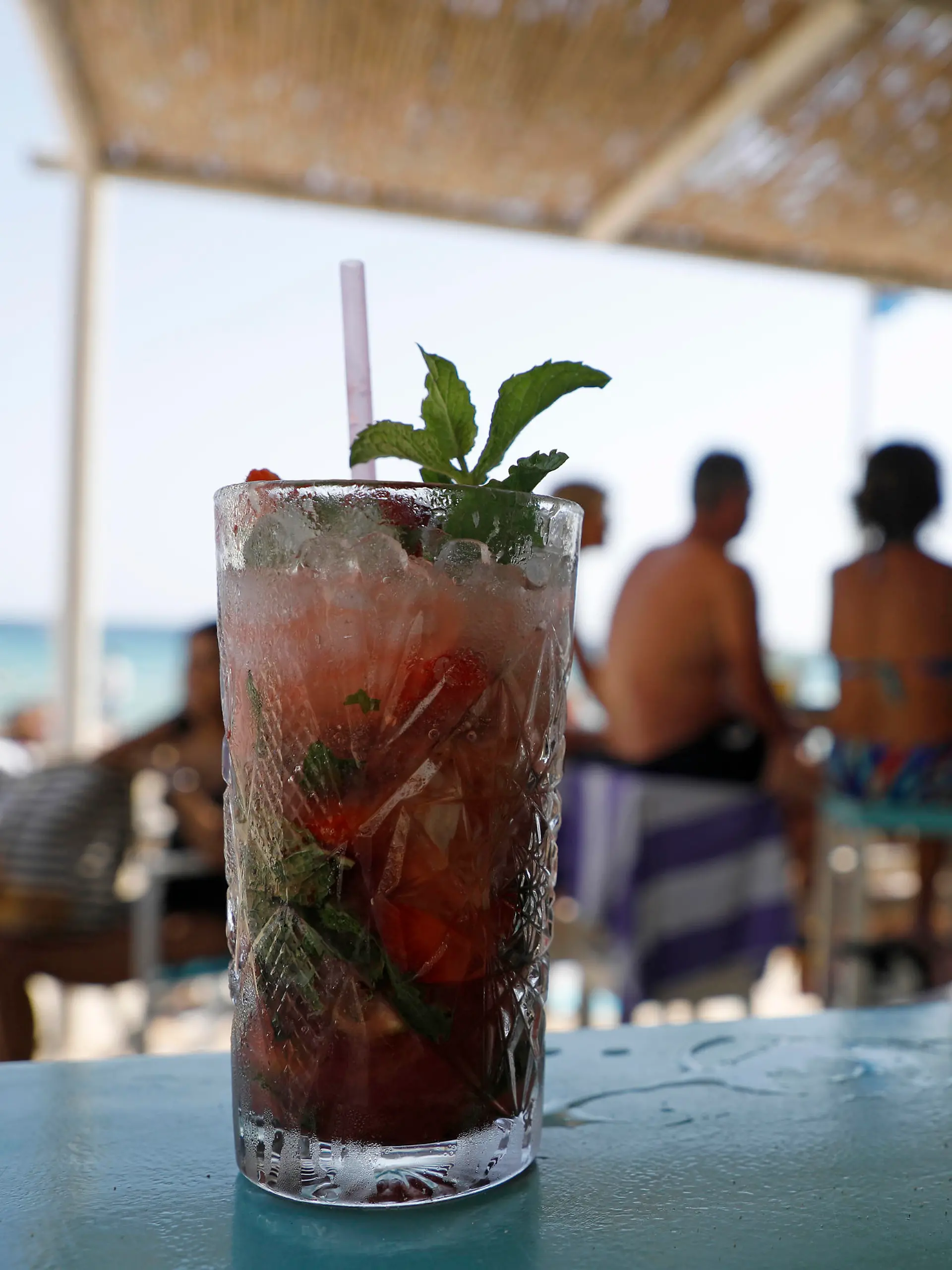 Menschen sitzen in einer Bar am Strand von Cala Major, in der Nähe von Palma auf Mallorca. Im Vordergrund steht ein Drink - ein Mojito. Auf der spanischen Urlaubsinsel sind in diesen Tagen nicht nur der Sand und die Luft sehr heiß, sondern auch das Meereswasser erreicht ungewöhnlich hohe Temperaturen. (zu dpa Hitze auf Mallorca - Meer vor dem «Ballermann» wird zur warmen Brühe)