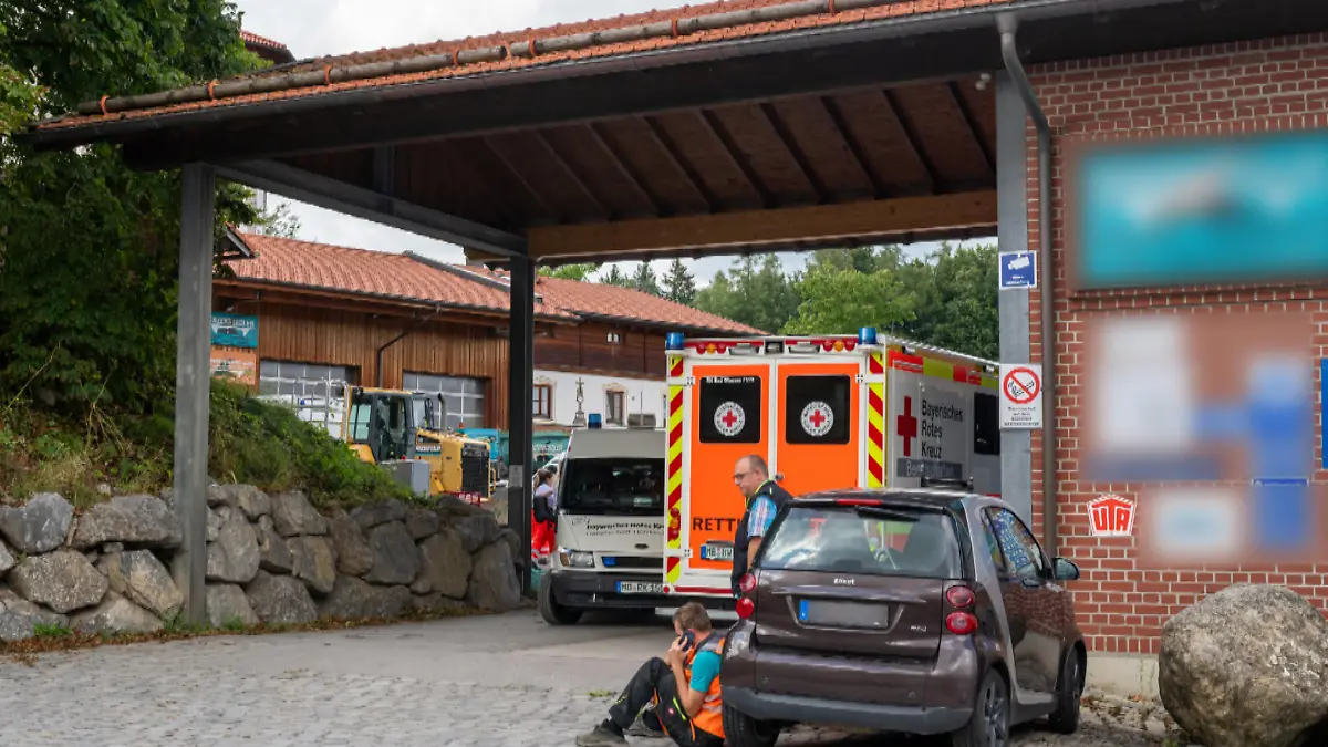Ein Krankenwagen steht in der Einfahrt eines Unternehmens. Bei einem Arbeitsunfall in einer Entsorgungsfirma in Oberbayern sind drei Männer in einem Kanalsystem ertrunken.