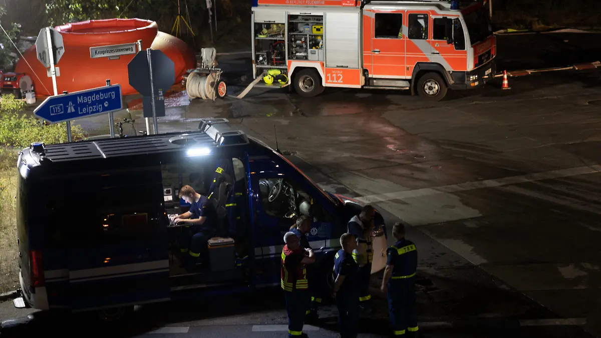 04.08.2022, Berlin: Feuerwehrkräfte und Mitarbeiter des technischen Hilfswerkes (THW) sind in der Nacht im Einsatz an der Autobahnbrücke Hüttenweg, von wo Löschfahrzeuge zum Einsatz an die Brandstelle im Grunewald fahren. Am Morgen ist ein Feuer auf dem Sprengplatz der Polizei im Grunewald ausgebrochen. Durch den Brand ist es am frühen Abend erneut zu Explosionen gekommen. Foto: Christian Ender/dpa +++ dpa-Bildfunk +++
