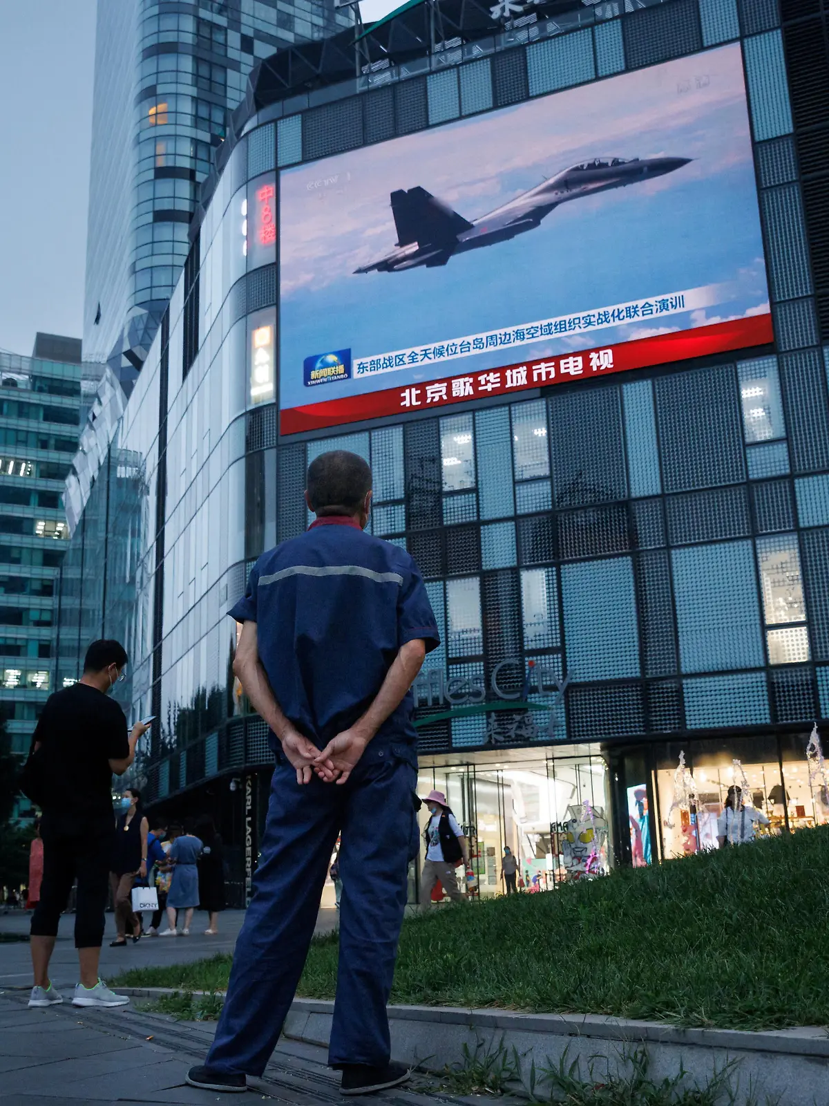 A man watches a CCTV news broadcast, showing a fighter jet during joint military operations near Taiwan by the Chinese People's Liberation Army's (PLA) Eastern Theatre Command, at a shopping center in Beijing, China, August 3, 2022. REUTERS/Thomas Peter