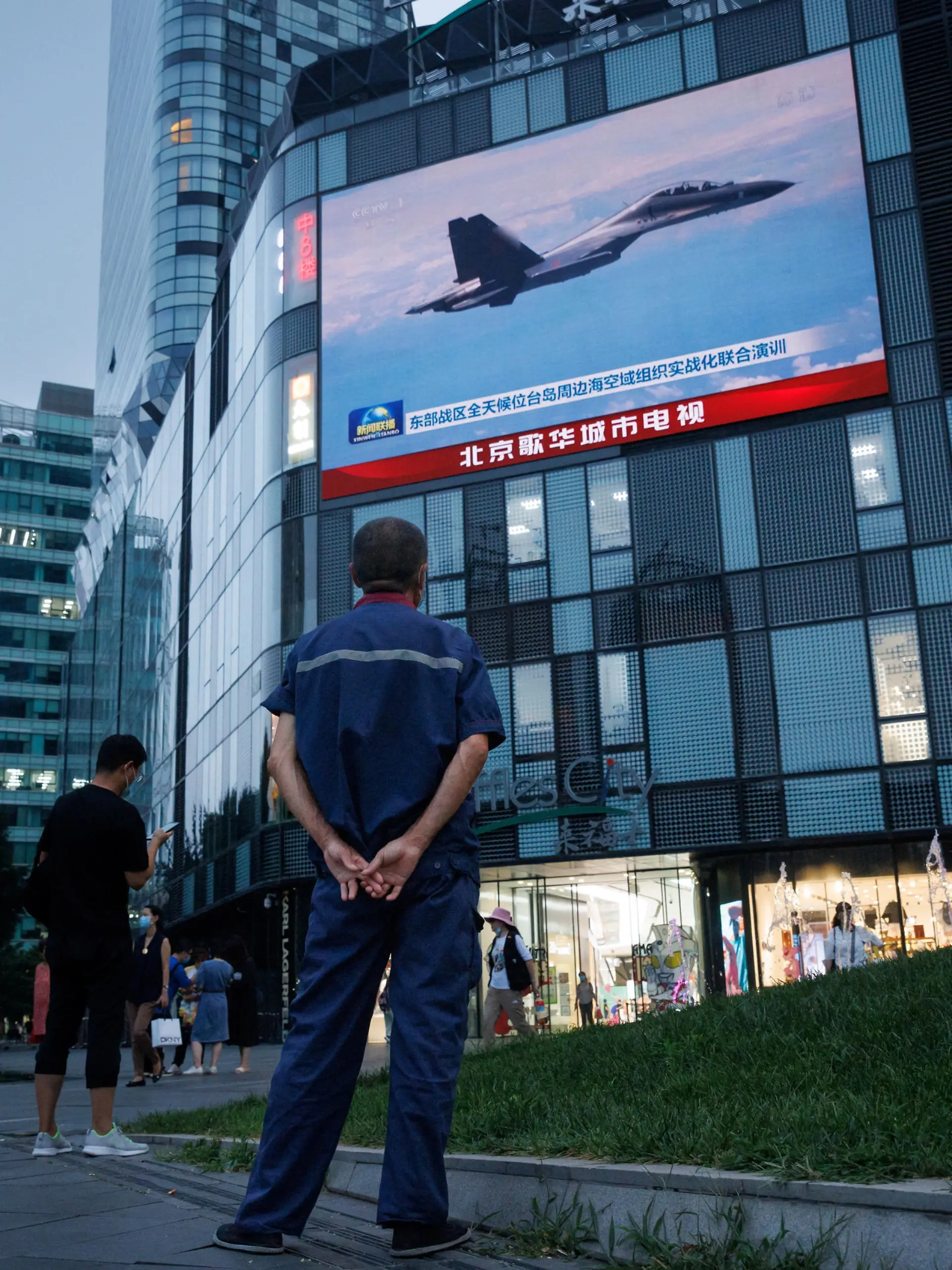 A man watches a CCTV news broadcast, showing a fighter jet during joint military operations near Taiwan by the Chinese People's Liberation Army's (PLA) Eastern Theatre Command, at a shopping center in Beijing, China, August 3, 2022. REUTERS/Thomas Peter
