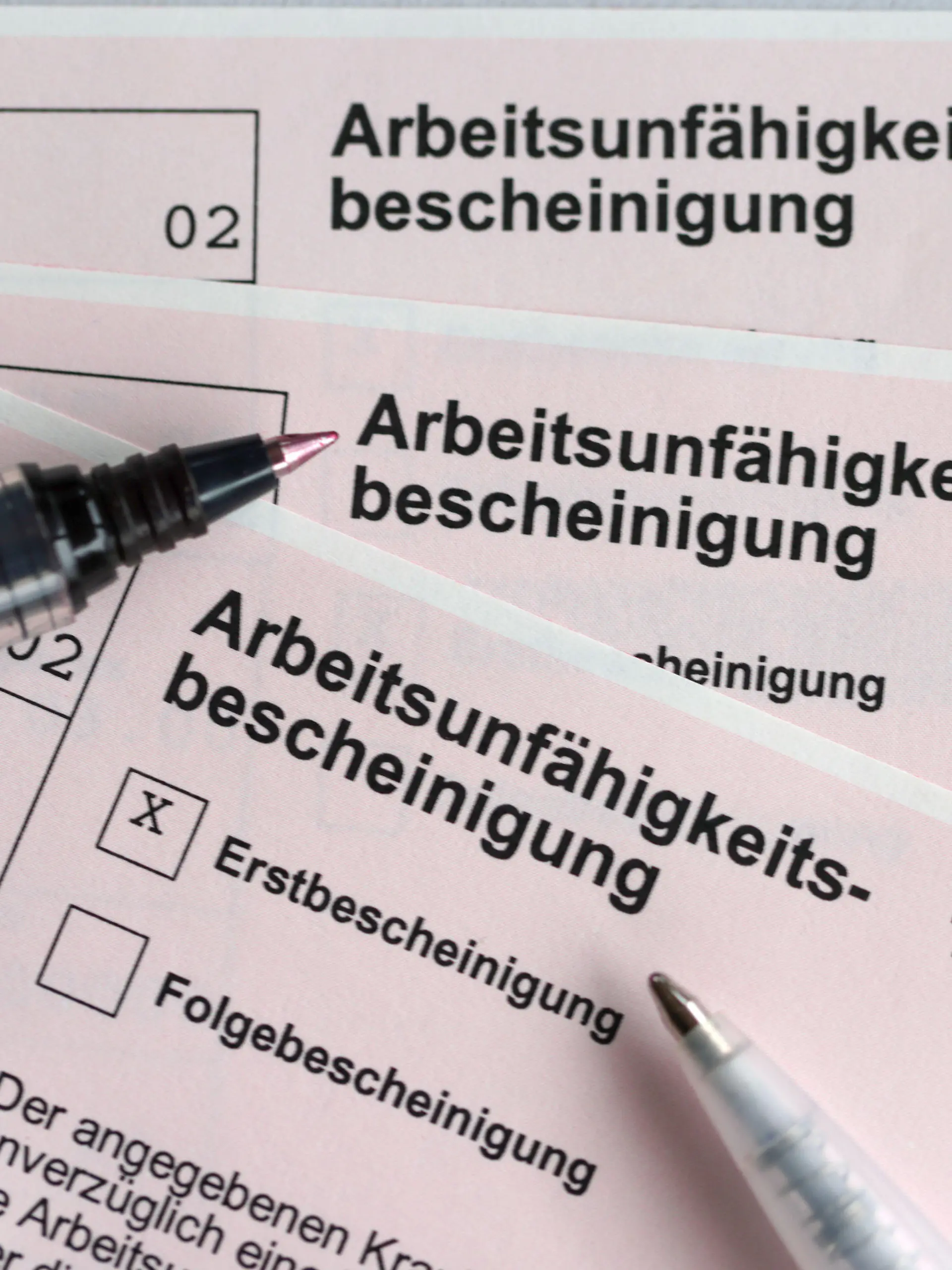 ARCHIV - 14.01.2022, Schleswig-Holstein, Kiel: Stifte liegen auf den Arbeitsunfähigkeitsbescheinigungen für Arbeitnehmer im Falle einer Krankschreibung durch den Arzt. (zu dpa: «Fehlzeiten wegen psychischer Erkrankungen im Norden gestiegen») Foto: Jens Büttner/dpa-Zentralbild/dpa +++ dpa-Bildfunk +++