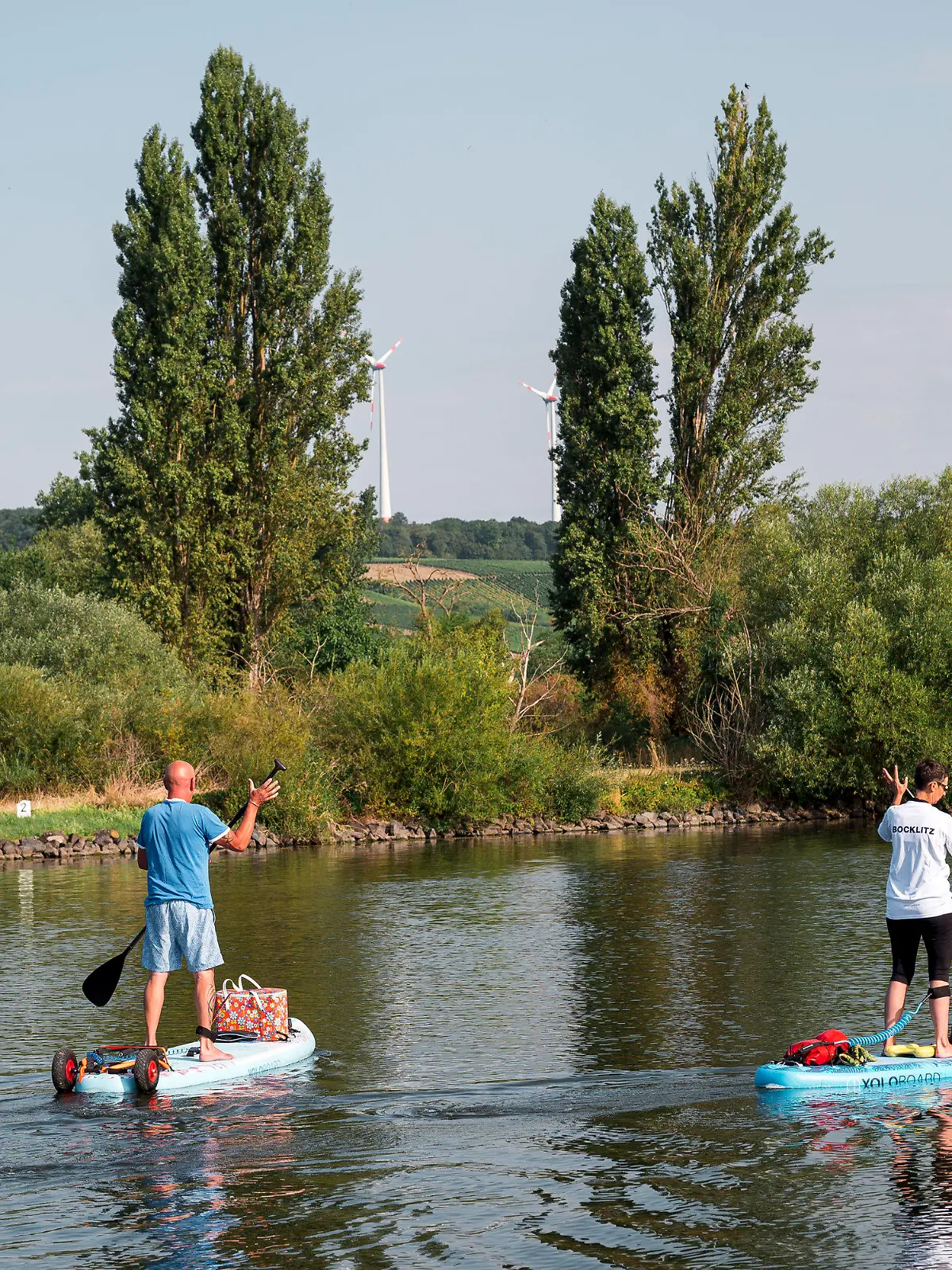 30.07.2022, Bayern, Volkach: Zwei Stand-up Paddler fahren auf dem Main zusammen mit ihrem Hund an Board entlang. Foto: Daniel Vogl/dpa +++ dpa-Bildfunk +++