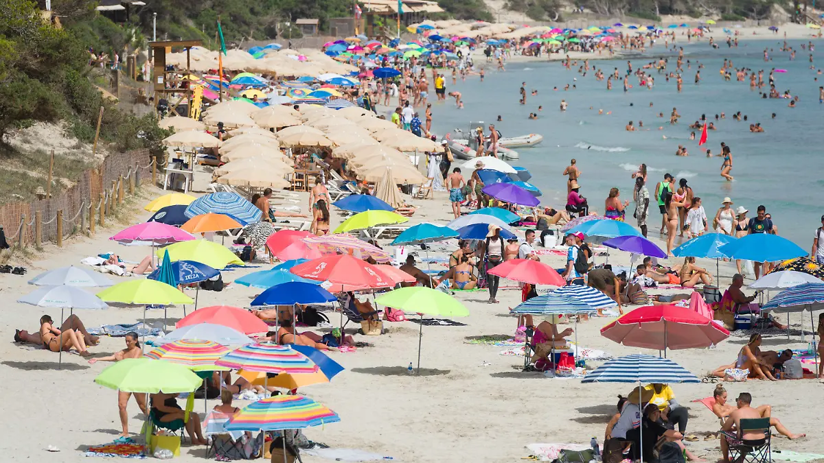 11.07.2023, Spanien, Ibiza: Menschen genießen einen Tag am Strand Ses Salines. Nach Informationen des Hotelverbandes der Pityusen ist in der Tourismusbranche der Insel ein starker Rückgang zu verzeichnen. Foto: Germán Lama/EUROPA PRESS/dpa +++ dpa-Bildfunk +++