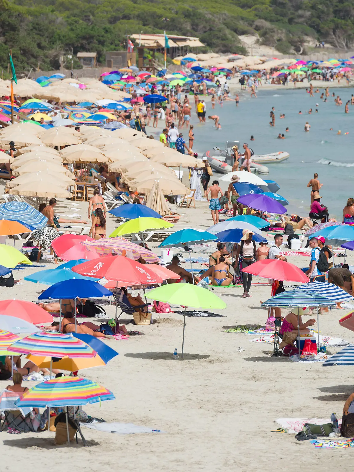 11.07.2023, Spanien, Ibiza: Menschen genießen einen Tag am Strand Ses Salines. Nach Informationen des Hotelverbandes der Pityusen ist in der Tourismusbranche der Insel ein starker Rückgang zu verzeichnen. Foto: Germán Lama/EUROPA PRESS/dpa +++ dpa-Bildfunk +++