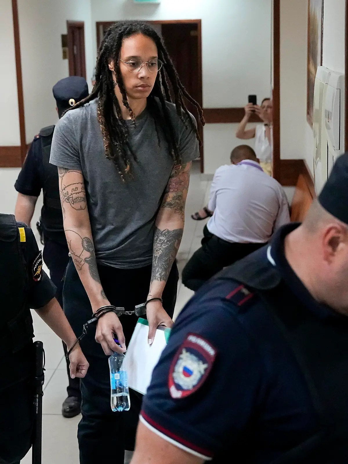 WNBA star and two-time Olympic gold medalist Brittney Griner is escorted in a court room prior to a hearing, in Khimki just outside Moscow, Russia, Thursday, Aug. 4, 2022. Closing arguments in Brittney Griner's cannabis possession case are set for Thursday, nearly six months after the American basketball star was arrested at a Moscow airport in a case that reached the highest levels of US-Russia diplomacy. (AP Photo/Alexander Zemlianichenko)