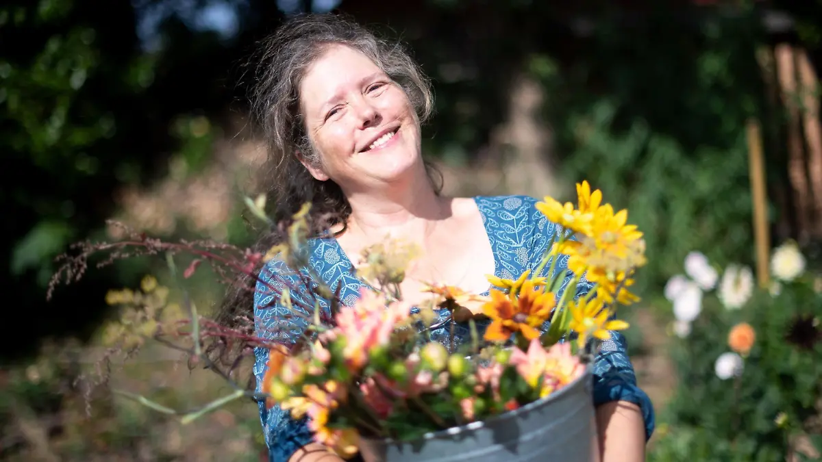 PRODUKTION - 29.07.2022, Bremen: Claudia Werner steht mit einem Eimer mit frisch geschnittenen Blumen in ihrem Garten. Die Bewegung SlowFood ist längst keine Randerscheinung mehr, nun gibt es auch die bundesweite Bewegung SlowFlowers. Mitglieder sind Floristinnen, Gärtner, Farmerinnen und Kollektive. Sie setzen sich für einen nachhaltigen, regionalen und saisonalen Schnittblumenanbau ein. (zu dpa: «Slow Flower»-Bewegung setzt auf nachhaltige Schnittblumen) Foto: Sina Schuldt/dpa +++ dpa-Bildfunk +++