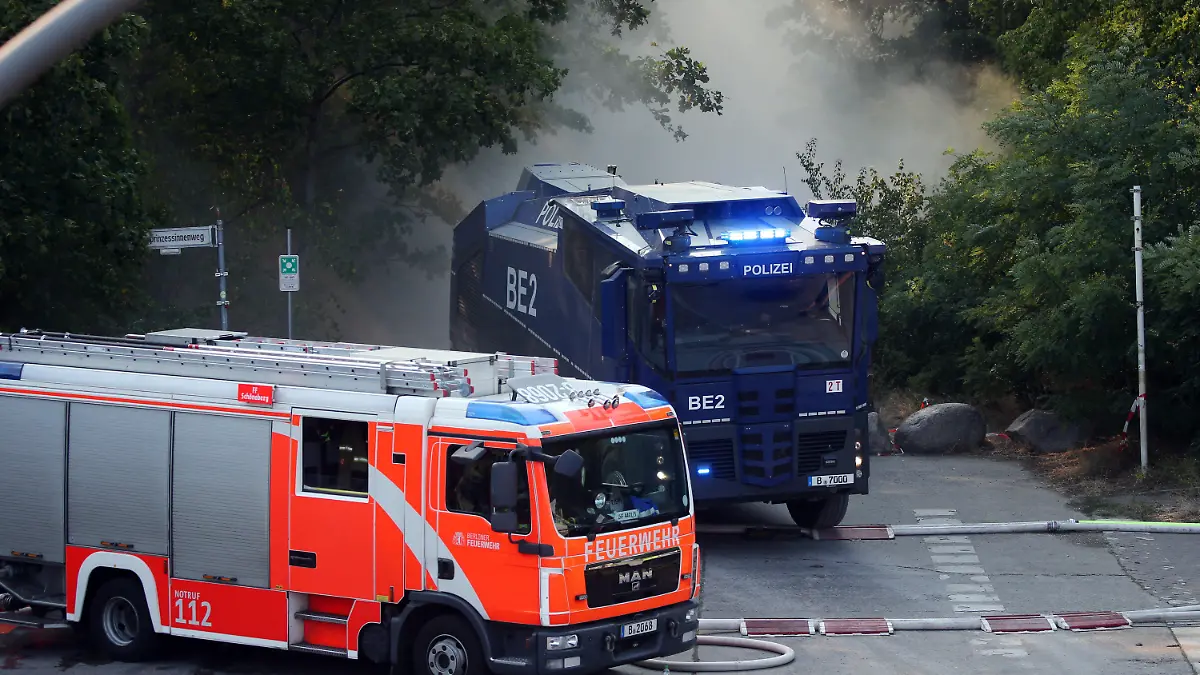 04.08.2022, Berlin: Ein Wasserwerfer der Polizei fährt zur Unterstützung der Löscharbeiten der Feuerwehr bei einem Waldbrand in den Grunewald. Durch einen Waldbrand im Grunewald, der nach Angaben der Polizei auf dem Sprengplatz ausgelöst wurde, sind Bahnlinien und Autobahnen in unmittelbarer Nähe gesperrt. Foto: Wolfgang Kumm/dpa +++ dpa-Bildfunk +++
