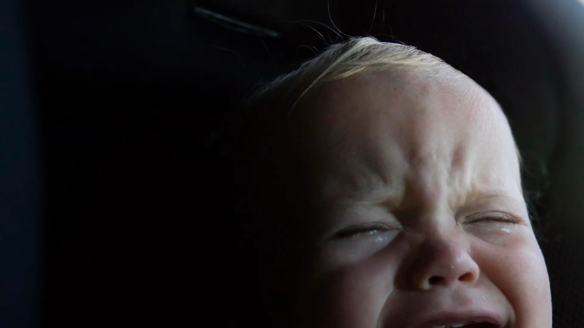 A 12 month ld baby boy crying in his car seat.