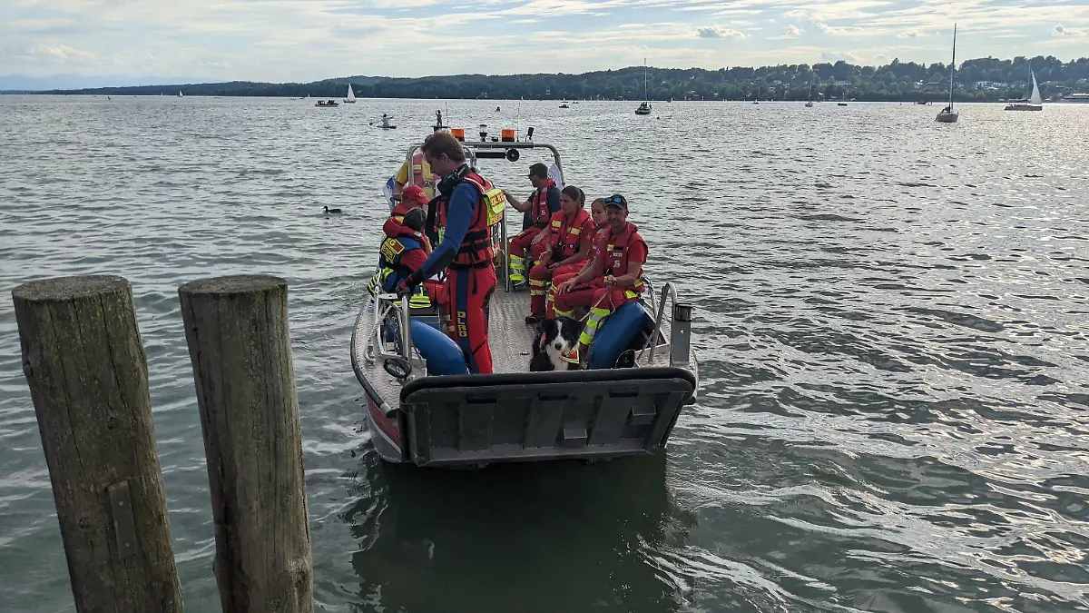 HANDOUT - 31.07.2022, Berg: Mitglieder der Wasserwacht und der DLRG sitzen während der Suche nach einem vermissten Schwimmer am Sonntag auf einem Boot im Starnberger See. Der 32-Jährige soll nach einem Zusammenstoß mit einem Motorboot untergegangen sein. (zu dpa: «Suche nach vermissten Schwimmer im Starnberger See geht weiter») Foto: Kreiswasserwacht Starnberg/dpa - ACHTUNG: Nur zur redaktionellen Verwendung im Zusammenhang mit der aktuellen Berichterstattung und nur mit vollständiger Nennung des vorstehenden Credits "Kreiswasserwacht Starnberg" +++ dpa-Bildfunk +++