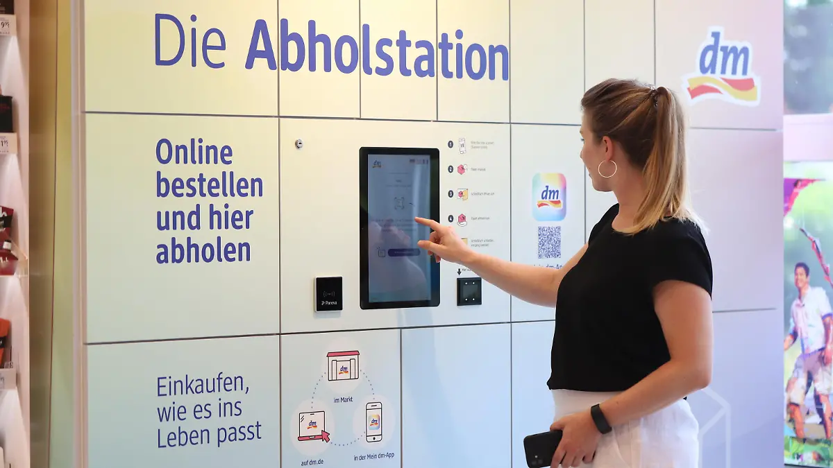 Kundin holt bestellte Waren an der Station in der dm-Filiale ab