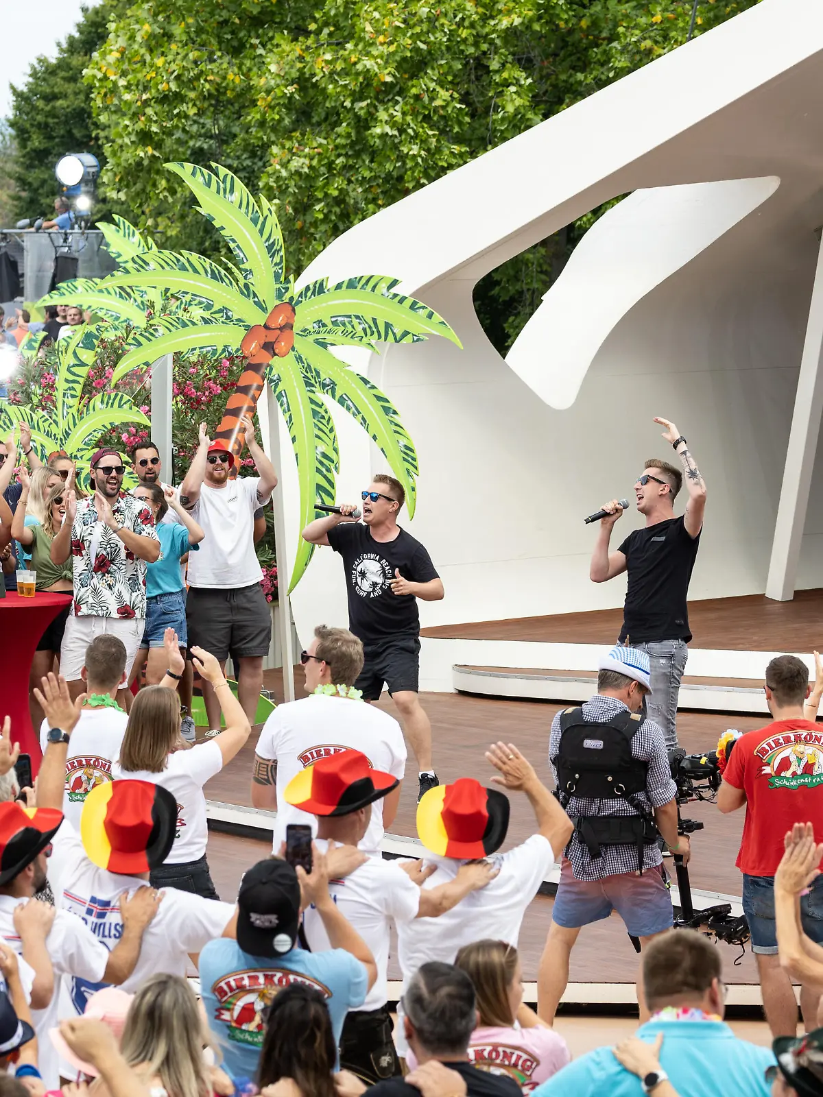 dpatopbilder - 31.07.2022, Rheinland-Pfalz, Mainz: Das Publikum feiert den Auftritt des Schlager-Duos DJ Robin & Schürze mit dem umstrittenen Song «Layla» im «ZDF-Fernsehgarten». Seit Wochen gibt es eine Sexismus-Debatte um ihr Lied. Der «Fernsehgarten» stand am Sonntag unter dem Partymotto «Mallorca vs. Oktoberfest». Foto: Hannes P. Albert/dpa +++ dpa-Bildfunk +++