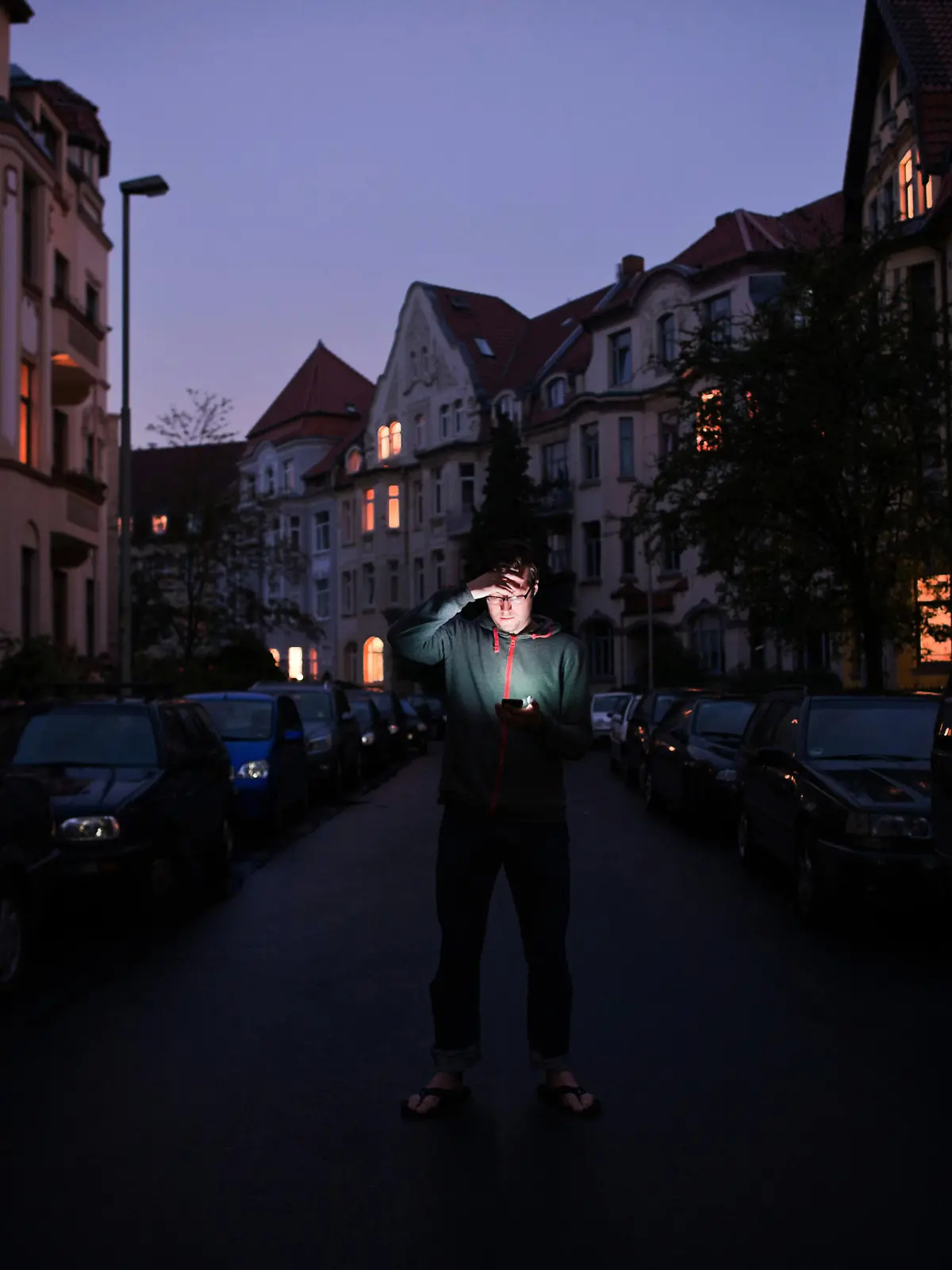 Ein Mann steht am Mittwoch (13.07.2011) während eines Stromausfalls in der Nordstadt in Hannover und schaut auf das Display seines Handys. Aus einigen Wohnungen schimmert Kerzenschein. Ein Stromausfall hat am Mittwochabend das gesamte Stadtgebiet von Hannover und anliegende Gemeinden verdunkelt. Foto: Christian Burkert dpa/lni