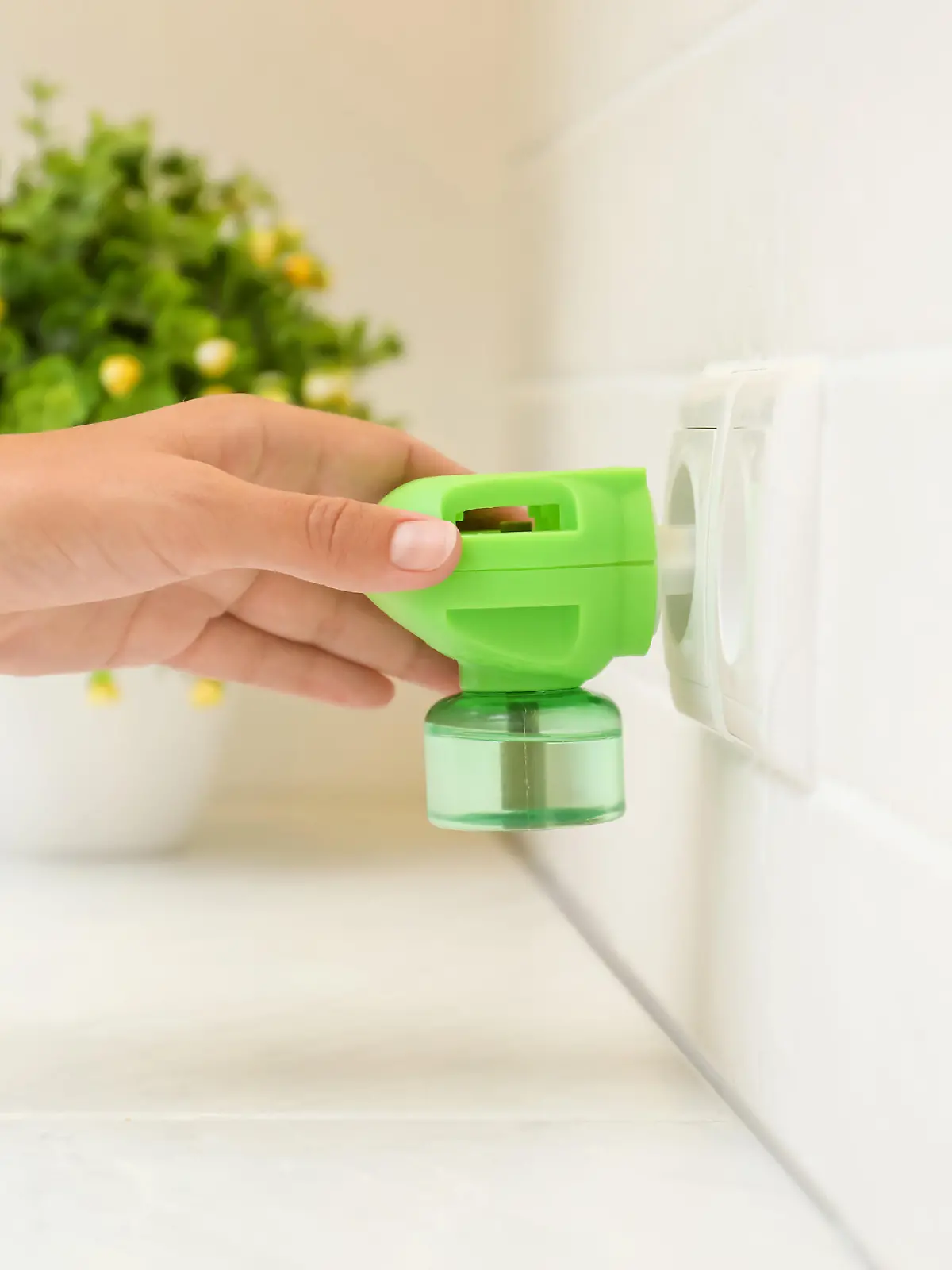 Woman plugging electric vaporizer with insect repellent liquid at home, closeup