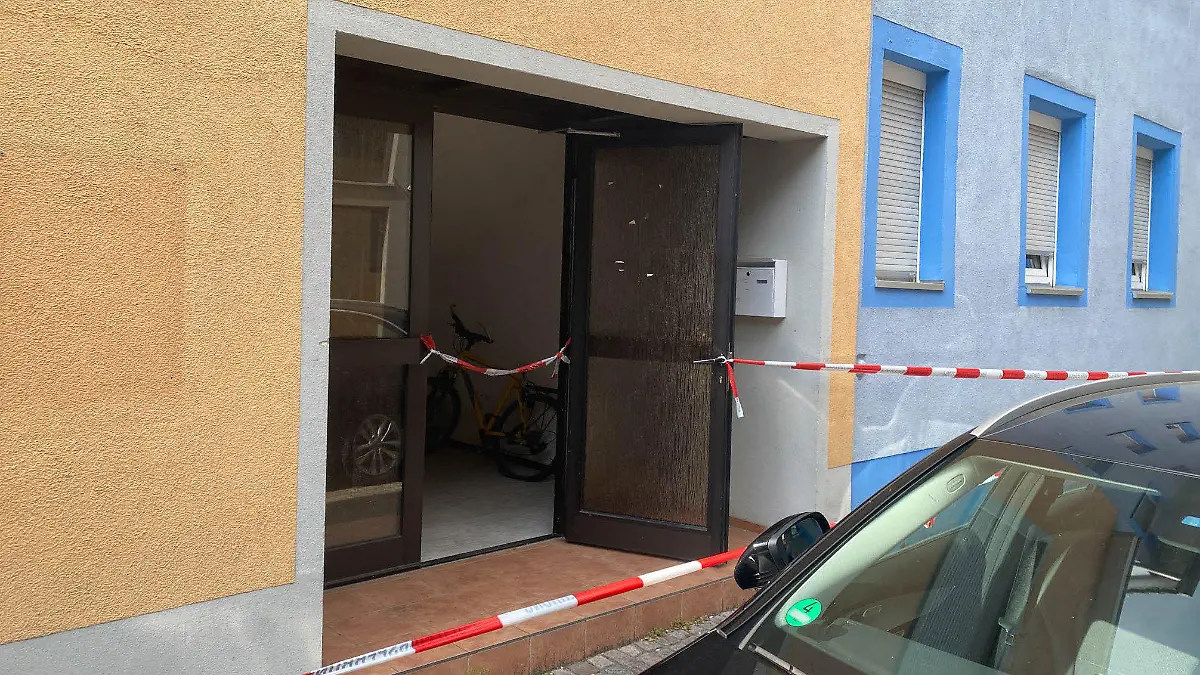 30.07.2022, Baden-Württemberg, Offenburg: Ein Blick auf einen mit Polizei-Absperrband abgeriegelten Hauseingang. In einem Zimmer in einer Unterkunft in Offenburg sind am Samstag zwei tote Frauen entdeckt worden. Foto: Marco Dürr/Einsatz-Report24/dpa - ACHTUNG: Nummer auf Auto wurde aus rechtlichen Gründen gepixelt +++ dpa-Bildfunk +++