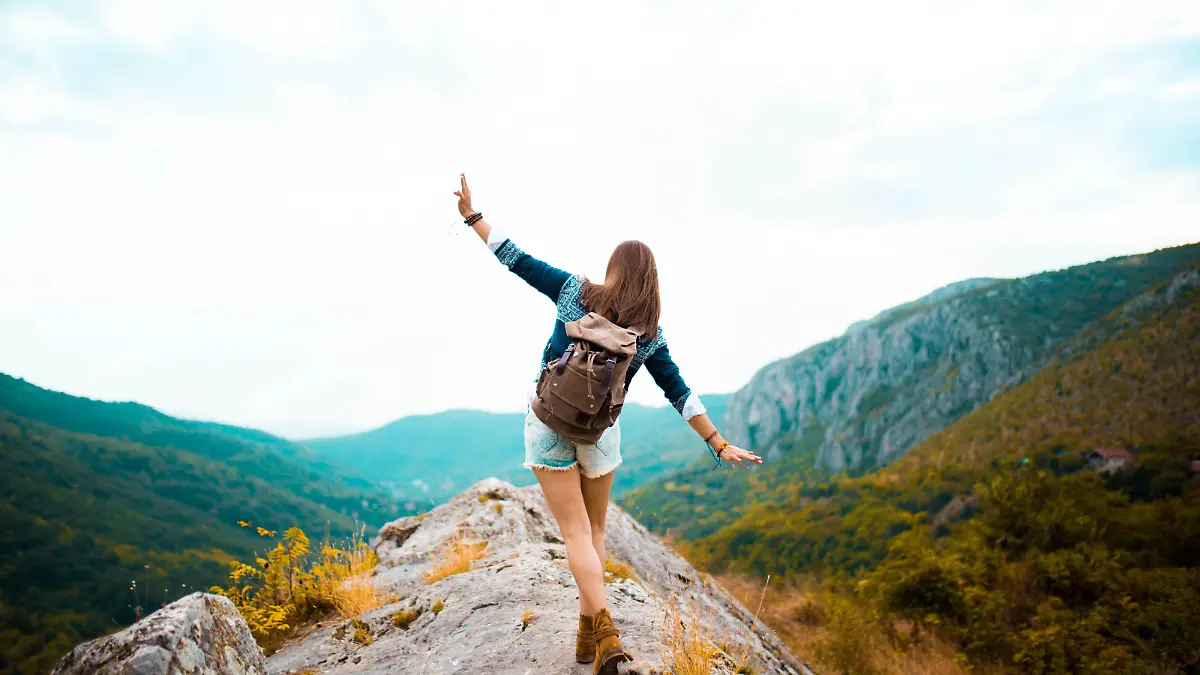 Young Hippie girl taking a walk on top of a mountain and enjoying the day. rear view