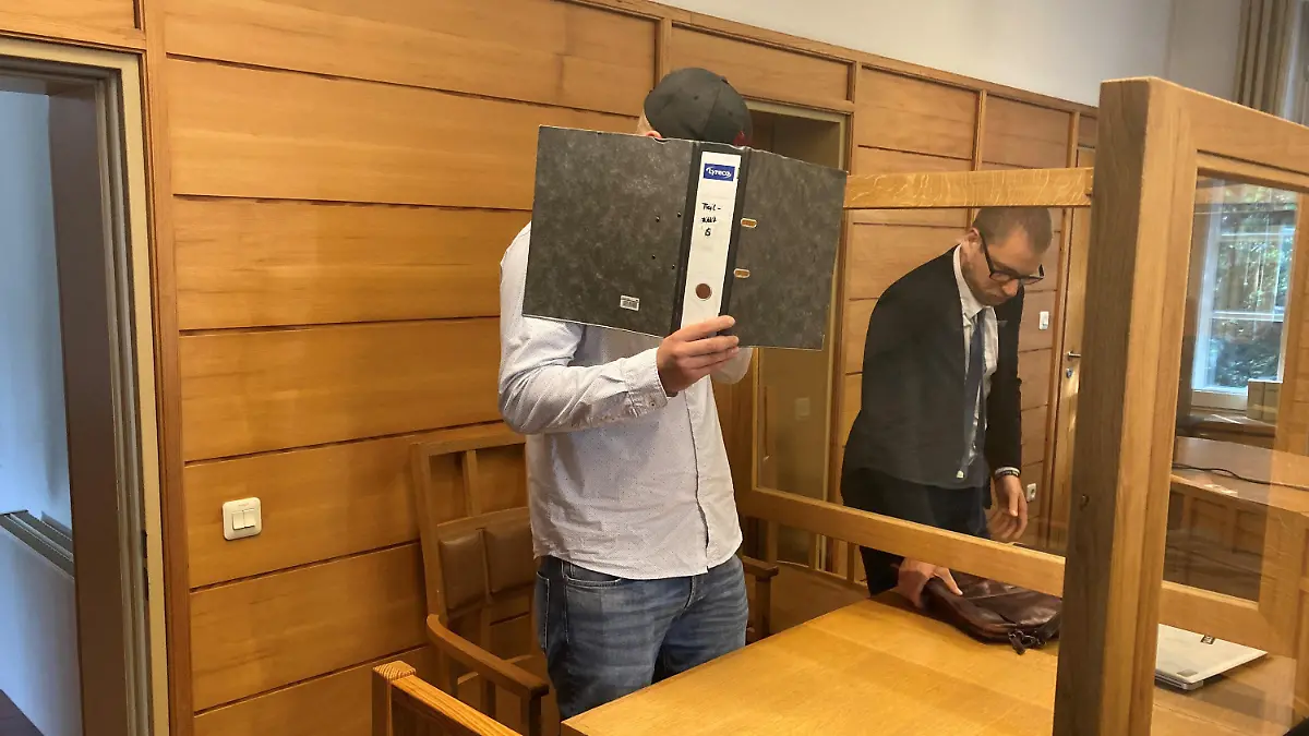 28.07.2022, Schleswig-Holstein, Bad Segeberg: Ein 22 Jahre alter Mann (l) steht vor dem Jugendschöffengericht in Bad Segeberg. Ihm wird vorgeworfen, im Oktober 2020 betrunken mit einem Auto einen Unfall verursacht zu haben, bei dem eine 16-Jährige starb. Foto: Sönke Möhl/dpa - ACHTUNG: Ein Schriftzug auf dem Ordner wurde aus rechtlichen Gründen gepixelt +++ dpa-Bildfunk +++