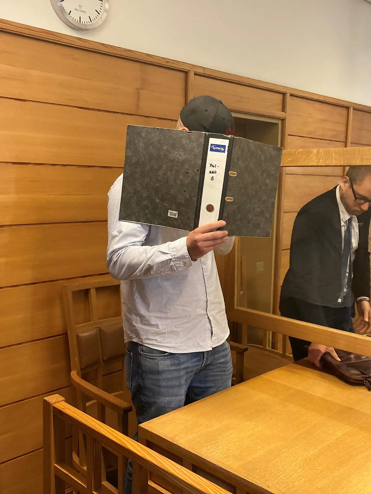 28.07.2022, Schleswig-Holstein, Bad Segeberg: Ein 22 Jahre alter Mann (l) steht vor dem Jugendschöffengericht in Bad Segeberg. Ihm wird vorgeworfen, im Oktober 2020 betrunken mit einem Auto einen Unfall verursacht zu haben, bei dem eine 16-Jährige starb. Foto: Sönke Möhl/dpa - ACHTUNG: Ein Schriftzug auf dem Ordner wurde aus rechtlichen Gründen gepixelt +++ dpa-Bildfunk +++