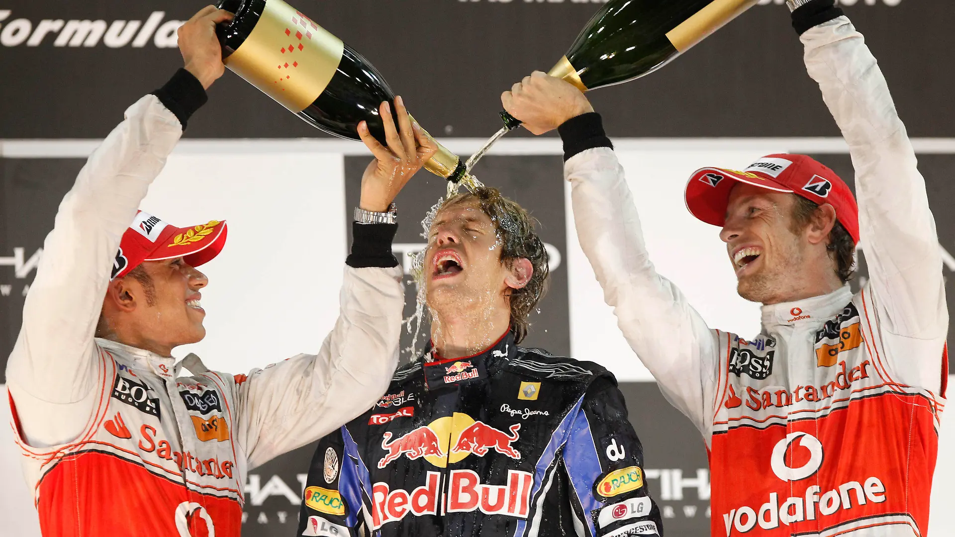 FILE - McLaren Mercedes driver Lewis Hamilton of Britain, left, and his teammate driver Jenson Button spray rose water on Formula One 2010 World Champion Red Bull driver Sebastian Vettel of Germany after he won the Emirates Formula One Grand Prix, in Abu Dhabi, UAE, Sunday, Nov.14, 2010. Four-time Formula One champion Sebastian Vettel says he will retire at the end of the season to spend more time with his family. The German driver won the F1 title from 2010-13 with the Red Bull team. His last race victory came with Ferrari in 2019. (AP Photo/Luca Bruno, File)