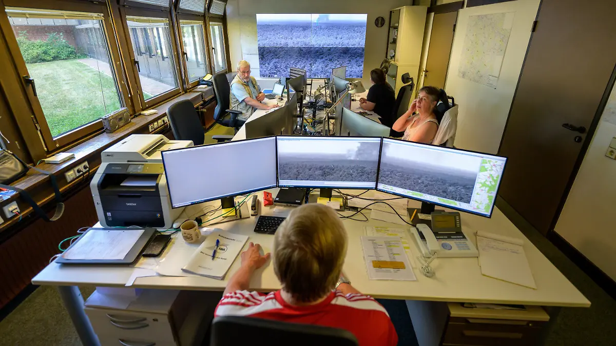 20.07.2022, Niedersachsen, Lüneburg: Toni Jankowski (vorn in der Mitte), Mitarbeiter der Waldbrandzentrale in Lüneburg, behält auf seinen Monitoren eine Rauchsäule im Blick. (Zu dpa "Waldbrandzentrale Lüneburg vor traurigem Rekord in 2022") Foto: Philipp Schulze/dpa - ACHTUNG: Verwendung nur im vollen Format +++ dpa-Bildfunk +++