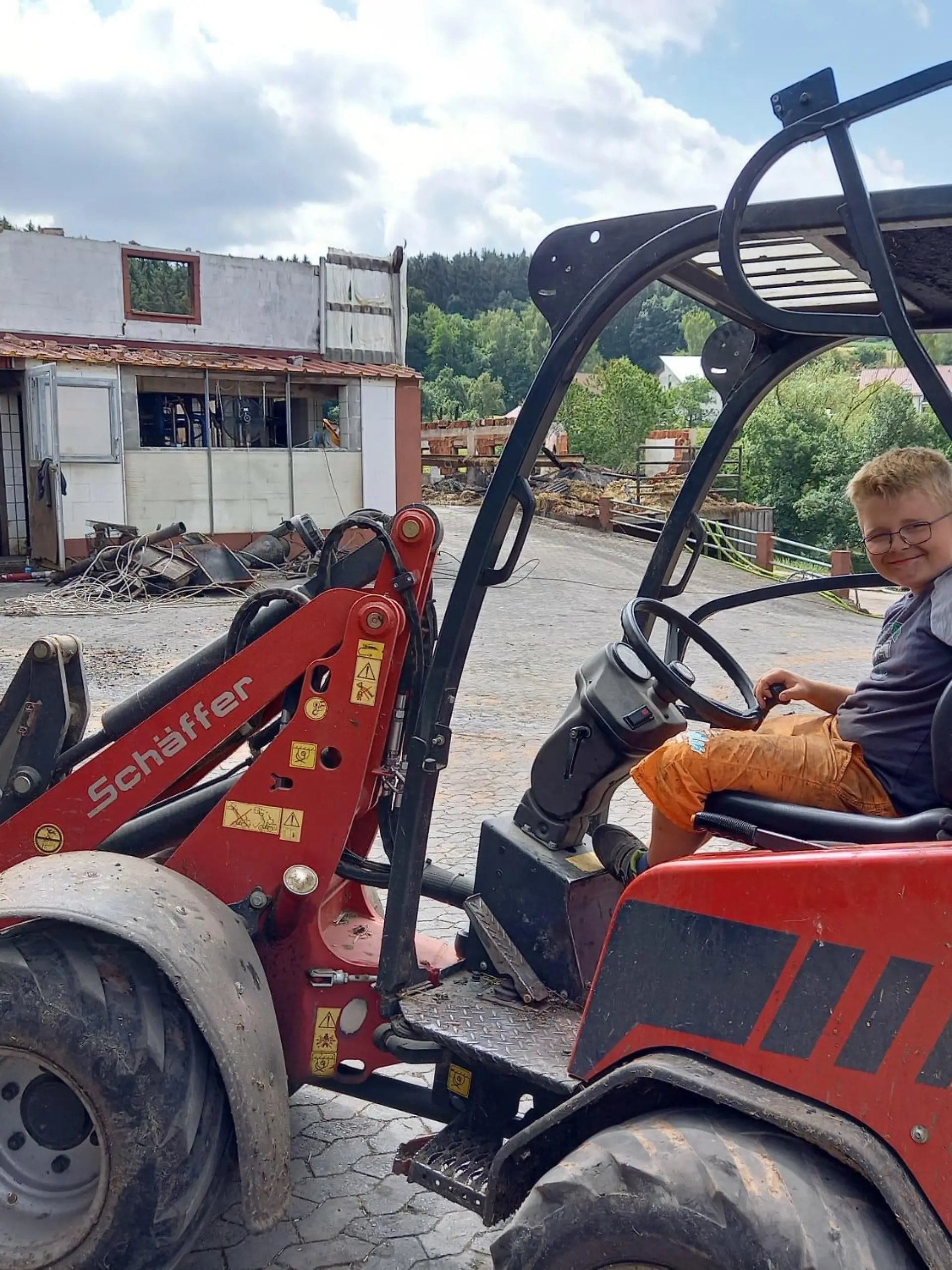 Ben (9) am Tag nach dem Brand auf dem elterlichen Hof: Auch beim Aufräumen nimmt er gerne alles selbst in die Hand - mit dem Radlader.