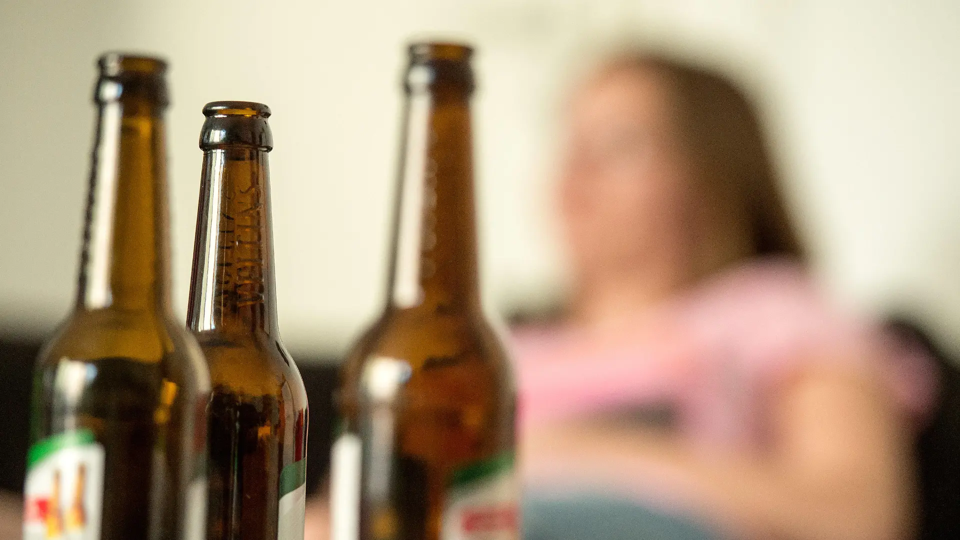 ILLUSTRATION - 28.05.2016, Berlin: Eine junge Frau sitzt hinter leeren Bierflaschen. (zu dpa: «Drogenberatung: Alkohol immer seltener das einzige Problem» vom 16.06.2018) Foto: Alexander Heinl/dpa +++ dpa-Bildfunk +++
