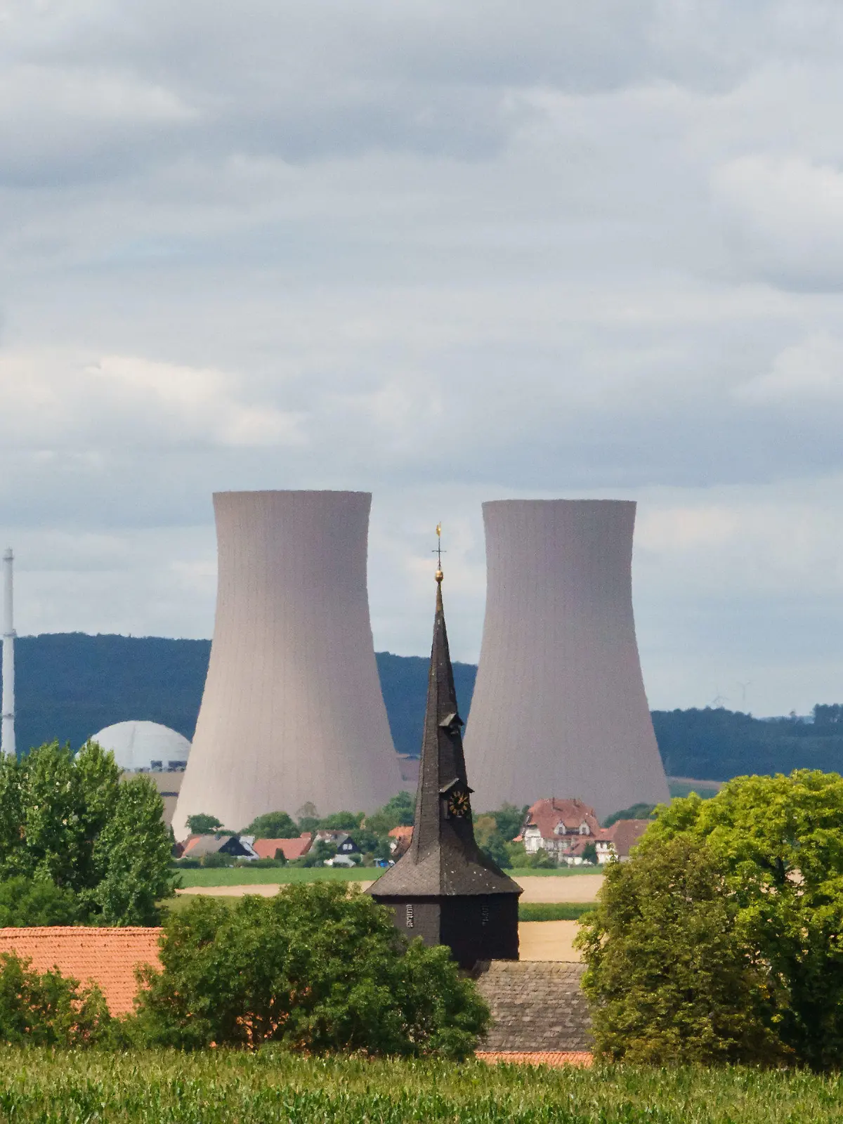 27.07.2022, Niedersachsen, Börry: Blick über den kleinen Ort Börry auf das stillgelegte Atomkraftwerk Grohnde. Der Tüv-Verband hält eine rasche Wiederinbetriebnahme der drei Atomkraftwerke für möglich, die Ende vergangenen Jahres stillgelegt wurden. Nach 36 Jahren war das Kernkraftwerk im Weserbergland bei Hameln am 31. Dezember 2021 vom Netz gegangen. Das niedersächsischen Umweltministerium rechnet derweil damit, dass die Genehmigung für den Rückbau des AKW Grohnde bis Jahresende 2022 erteilt wird. Foto: Melissa Erichsen/dpa +++ dpa-Bildfunk +++