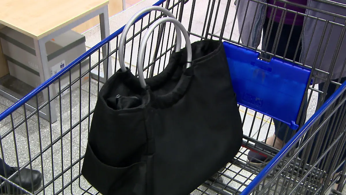 Eine Handtasche liegt vor Taschendieben ungeschützt im Einkaufswagen.