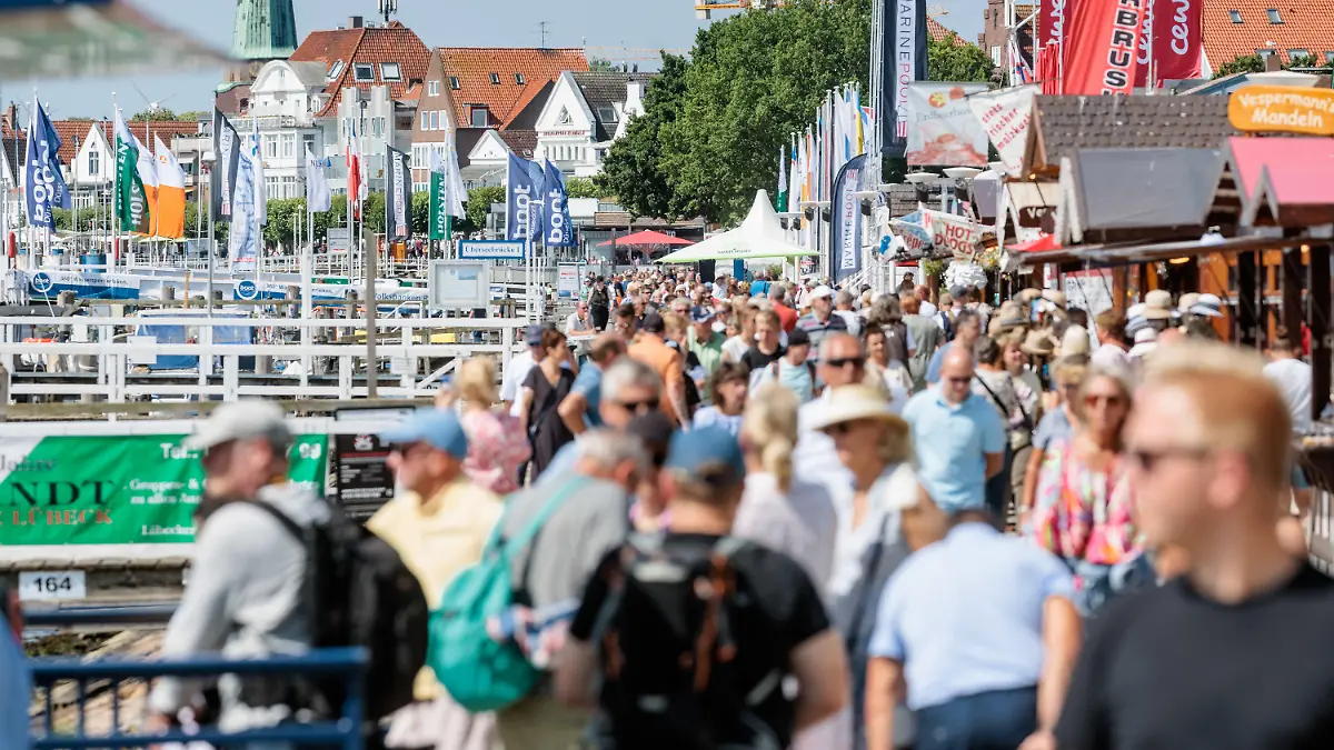 24.07.2022, Schleswig-Holstein, Lübeck-Travemünde: Bei strahlendem Sonnenschein und angenehmen 24 Grad Lufttemperatur flanieren Besucher auf der Travemünder Promenade. Foto: Markus Scholz/dpa +++ dpa-Bildfunk +++