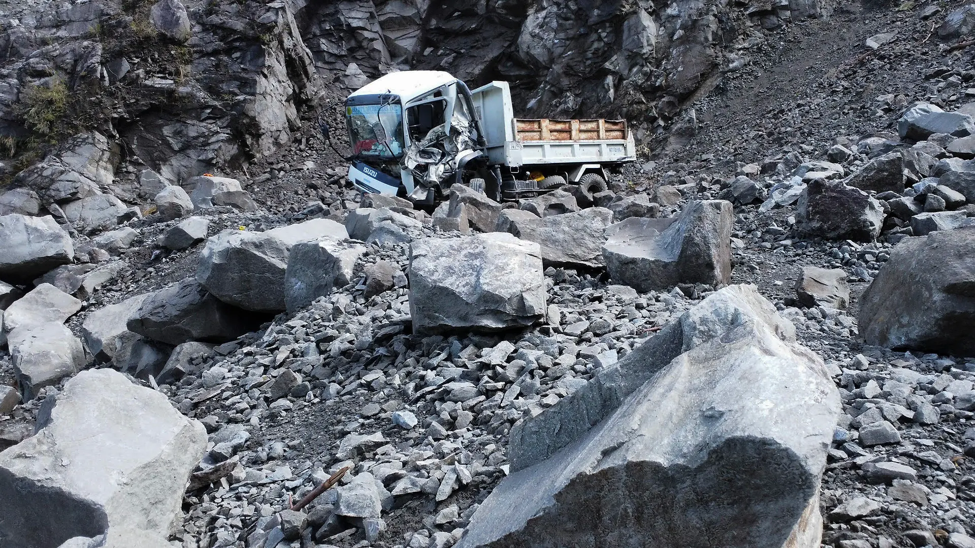27.07.2022, Philippinen, Bauko: Ein beschädigter Lastwagen liegt neben Felsbrocken, nachdem er während eines Erdbebens auf eine Straße gestürzt ist. Die Philippinen sind am heutigen Mittwochmorgen (Ortszeit) von einem heftigen Erdbeben erschüttert worden. Nach ersten Angaben des Instituts für Vulkanologie und Seismologie der Philippinen (Phivolcs) hatte das Beben eine Stärke von 7,3. Die US-Erdbebenwarte USGS bezifferte die Stärke auf 7,1. Das Epizentrum befand sich in dem Ort Lagangilang in der Provinz Abra. Foto: Harley Palangchao/AP/dpa +++ dpa-Bildfunk +++