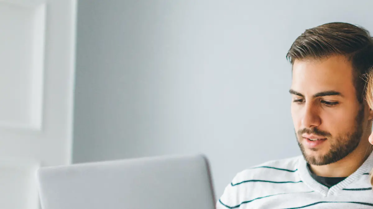 Young cheerful couple using laptop at home