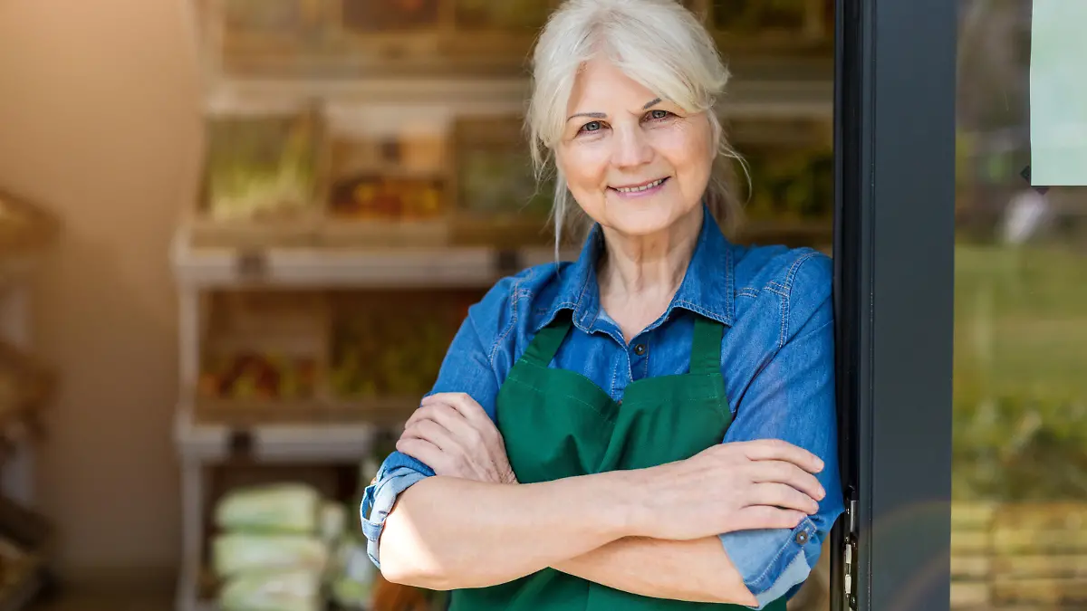 Portrait of confident owner with arms crossed standing in small grocery store