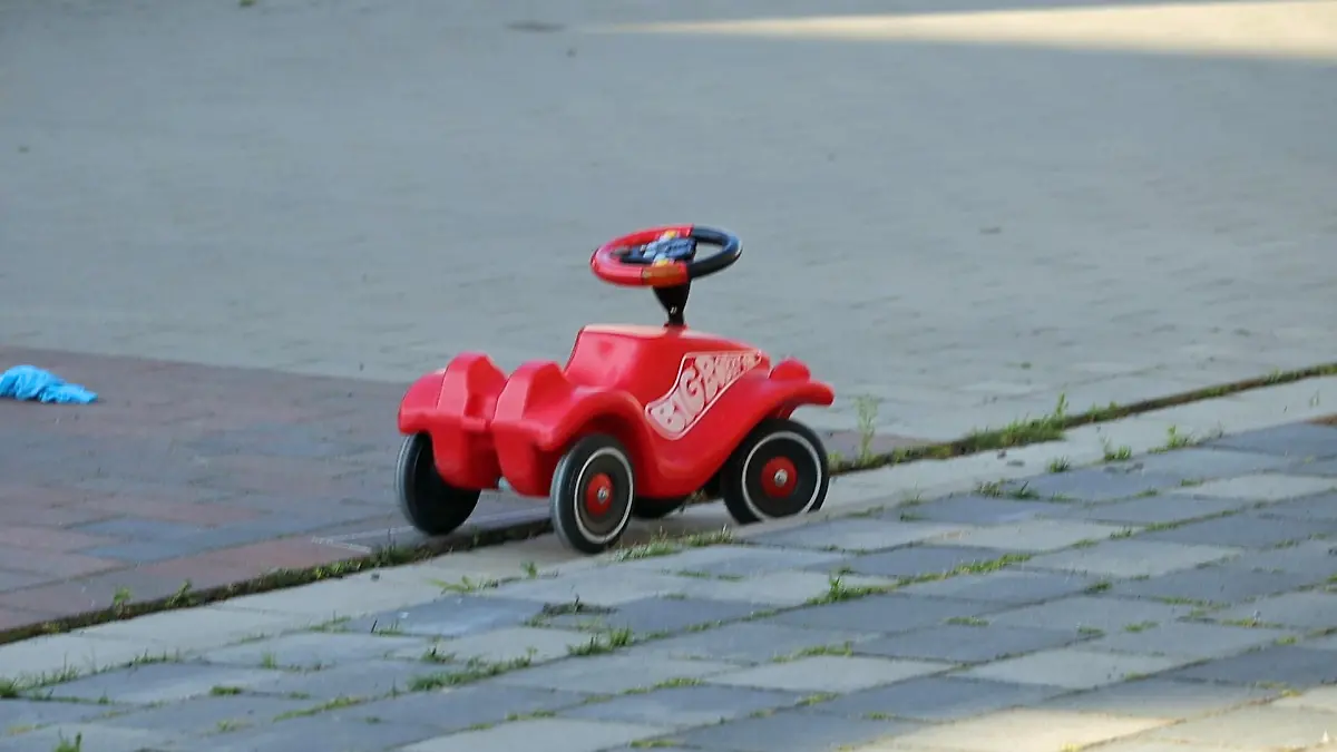 24.07.2022, Niedersachsen, Bohmte: Ein Bobbycar steht an einer verkehrsberuhigten Straße in Bohmte. Nach einem tödlichen Unfall in Bohmte im Landkreis Osnabrück, bei dem ein einjähriges Mädchen von einem Wagen überrollt wurde, hat die Polizei bei dem Autofahrer einen Atemalkoholwert von 0,8 Promille gemessen. Das Kleinkind war mit einem Bobbycar von einem Grundstück in einen verkehrsberuhigten Bereich gerollt. Dort kam es zum Zusammenstoß. Foto: Heinz-Jürgen Reiss/Nord-West-Media TV/dpa +++ dpa-Bildfunk +++