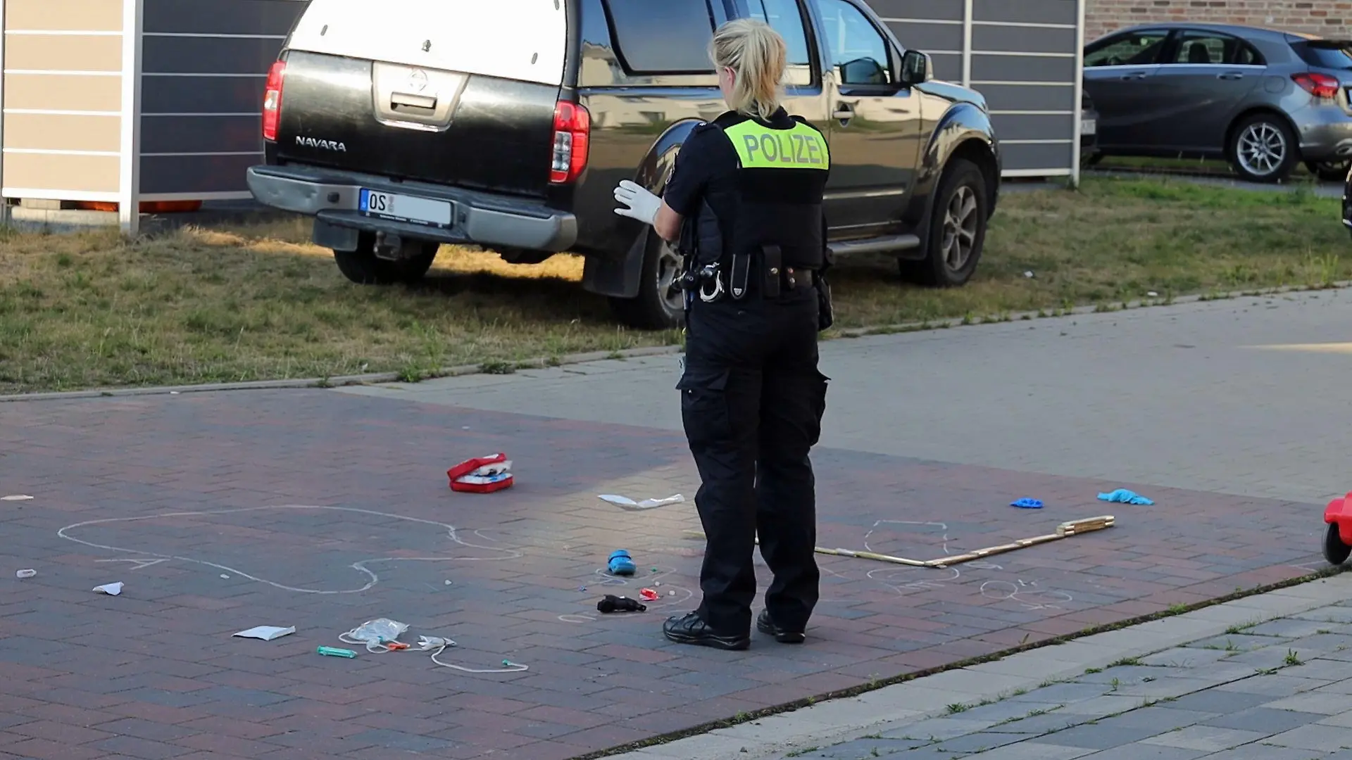 24.07.2022, Niedersachsen, Bohmte: Eine Polizistin sichert Spuren an einer Straße. Nach einem tödlichen Unfall in Bohmte im Landkreis Osnabrück, bei dem ein einjähriges Mädchen von einem Wagen überrollt wurde, hat die Polizei bei dem Autofahrer einen Atemalkoholwert von 0,8 Promille gemessen. Das Kleinkind war mit einem Bobbycar von einem Grundstück in einen verkehrsberuhigten Bereich gerollt. Dort kam es zum Zusammenstoß. Foto: Heinz-Jürgen Reiss/Nord-West-Media TV/dpa +++ dpa-Bildfunk +++
