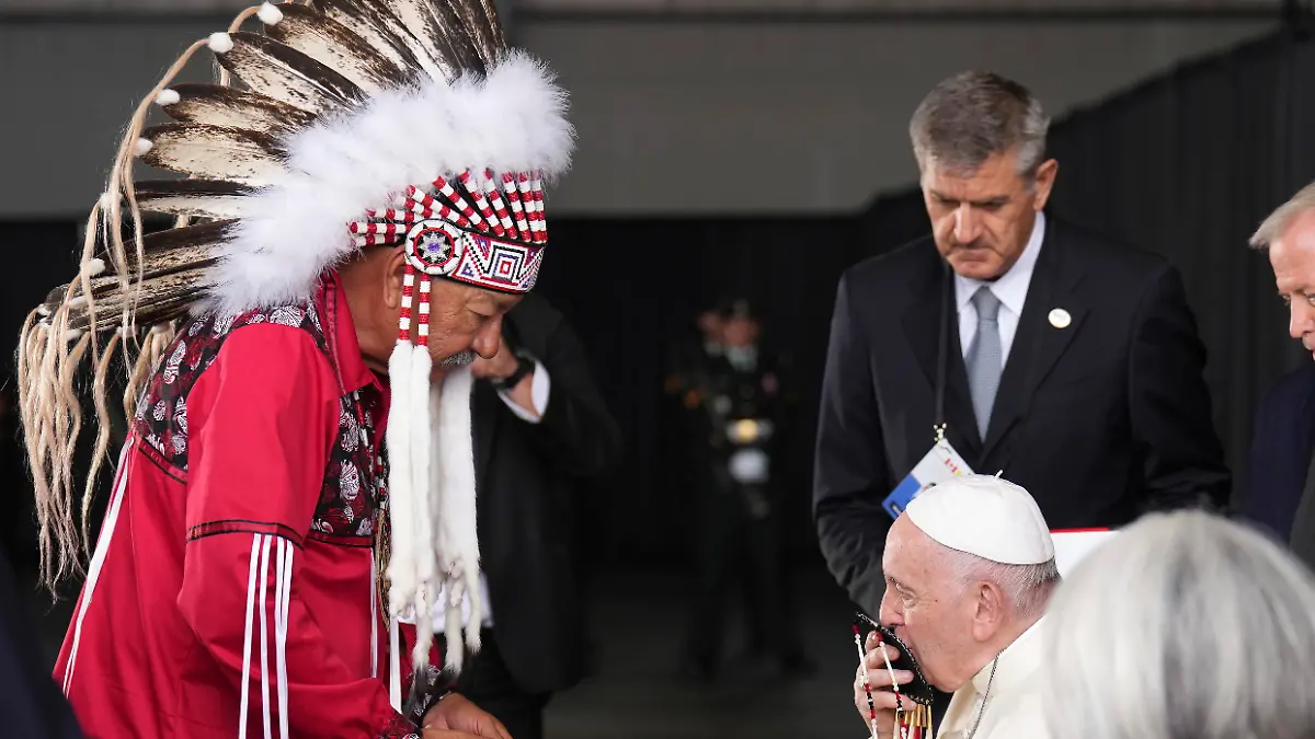 Pope Francis kisses a gift given to him by George Arcand, left, grand chief of the Confederacy of Treaty Six First Nations, as he arrives in Edmonton, Alberta, Canada, on Sunday, July 24, 2022. His visit to Canada is aimed at reconciliation with Indigenous people for the Catholic Church's role in residential schools. (Nathan Denette/The Canadian Press via AP)