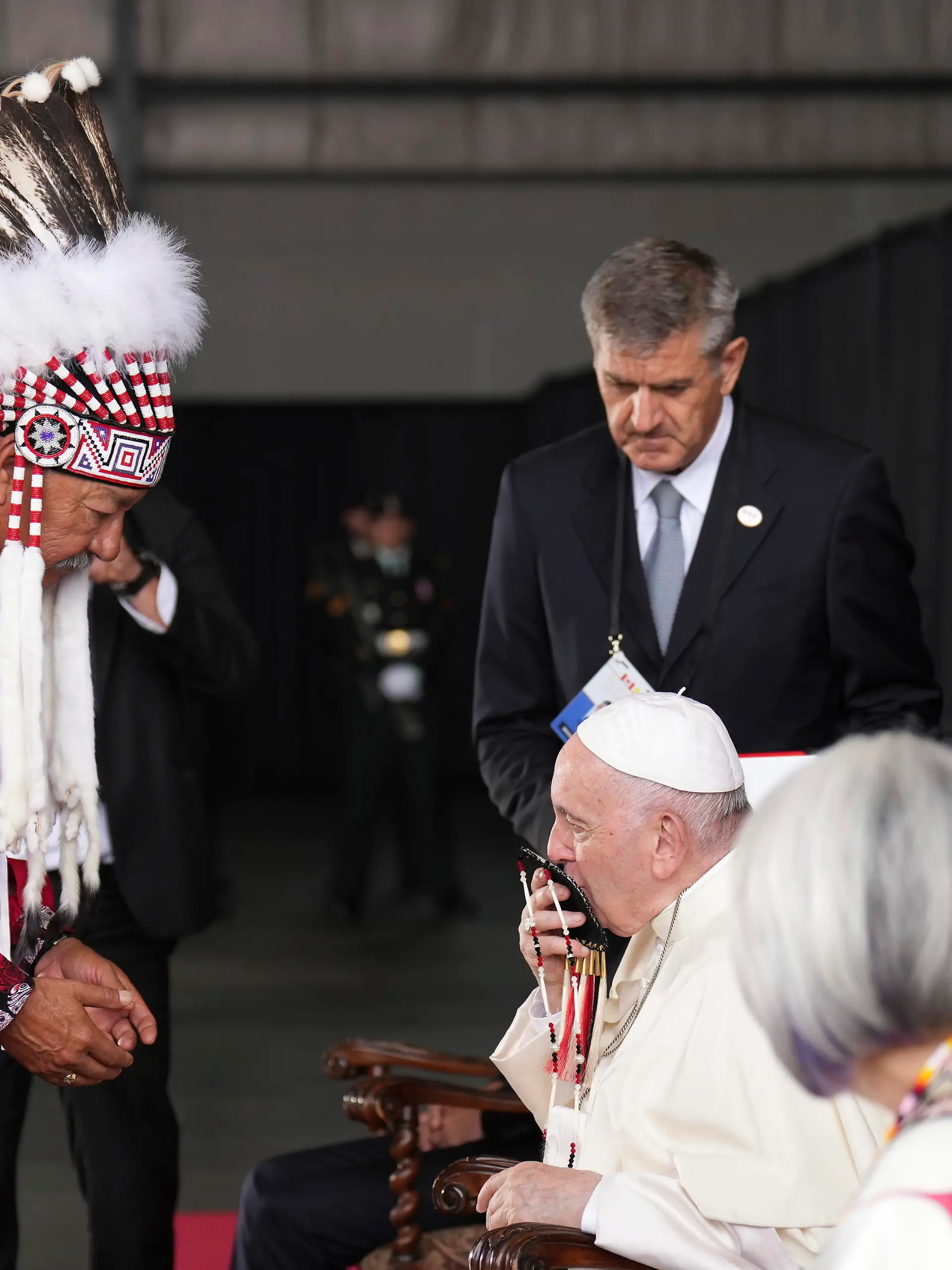 Pope Francis kisses a gift given to him by George Arcand, left, grand chief of the Confederacy of Treaty Six First Nations, as he arrives in Edmonton, Alberta, Canada, on Sunday, July 24, 2022. His visit to Canada is aimed at reconciliation with Indigenous people for the Catholic Church's role in residential schools. (Nathan Denette/The Canadian Press via AP)