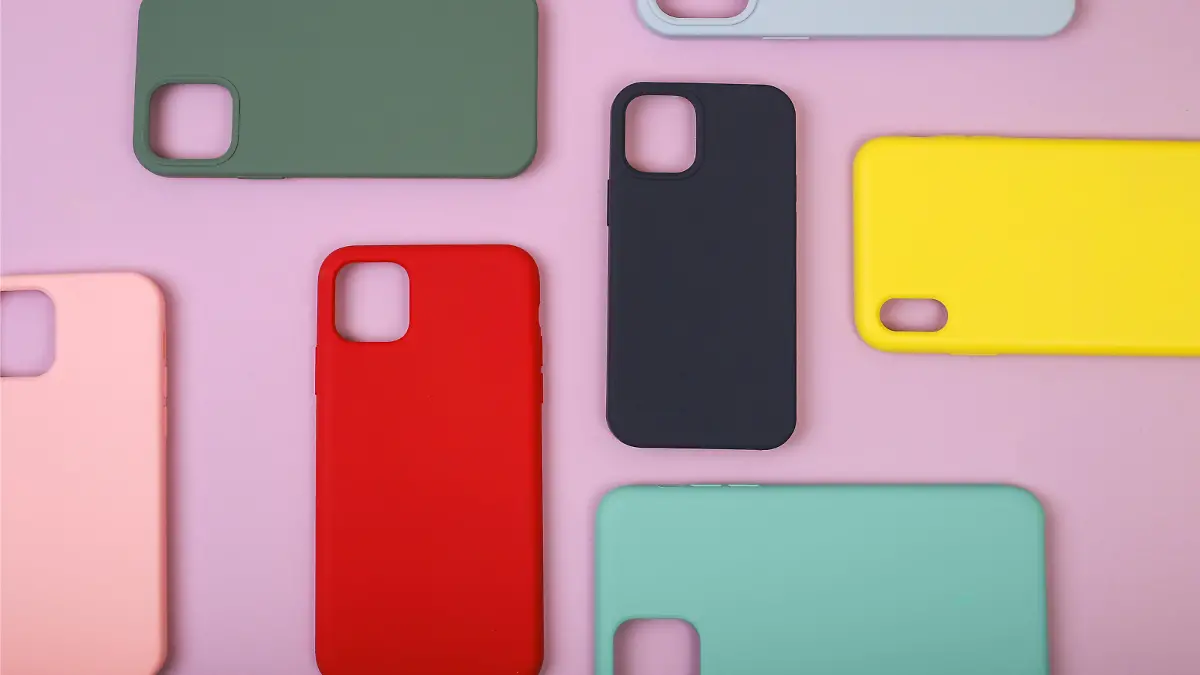 Colored silicone phone cases. Up to date technology.Close up of diverse personal accessory laying on the lavender background. Flat lay