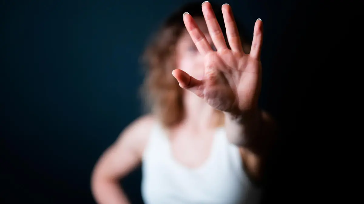 Close-up of a young woman making a stop gesture. Focus on foreground