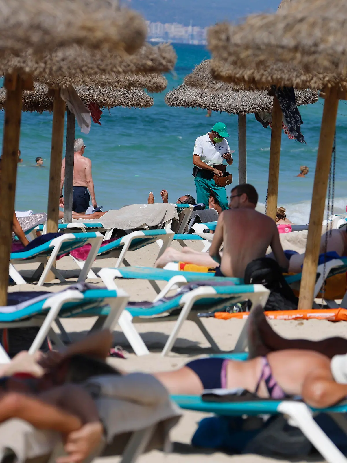 15.08.2020, Spanien, Palma: Menschen sonnen sich und schwimmen am Strand von Arenal auf Mallorca. Angesichts erhöhter Ansteckungsgefahren hat die Bundesregierung fast ganz Spanien einschließlich Mallorca als Risikogebiet eingestuft. Die Einstufung bedeutet, dass für heimkehrende Urlauber eine Testpflicht auf das Coronavirus greift. Foto: Clara Margais/dpa +++ dpa-Bildfunk +++