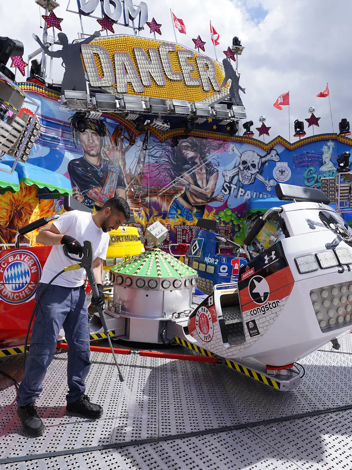 PRODUKTION - 15.07.2022, Hamburg: Ein Mitarbeiter reinigt das Fahrgeschäft Dom Dancer auf dem Heiligengeistfeld. Am 22. Juli wird das Volksfest, der Hamburger Sommerdom, eröffnet. Foto: Marcus Brandt/dpa +++ dpa-Bildfunk +++