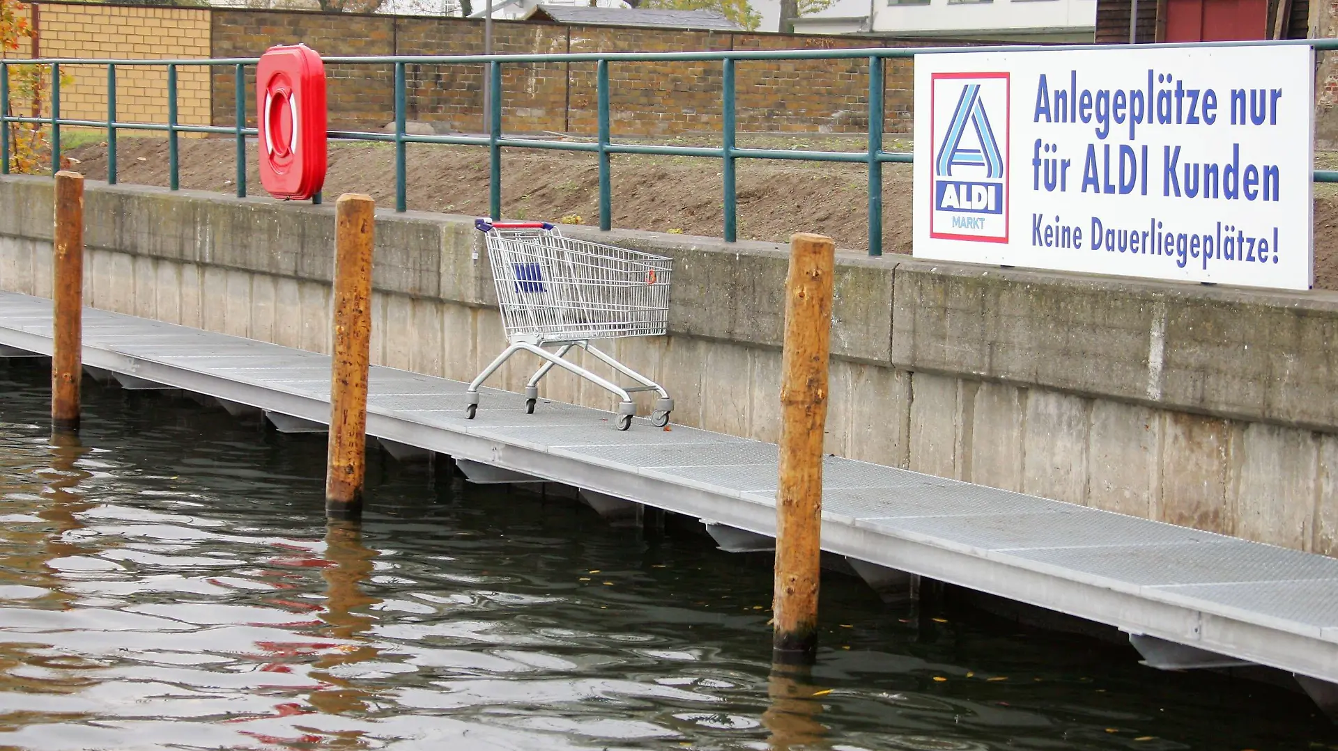 Potsdam (Brandenburg): Ein Einkaufswagen steht am 29.10.2004 in Potsdam an einem Bootssteg mit der Aufschrift "Anlegeplätze nur für ALDI Kunden. Keine Daueranliegeplätze!" in der Potsdamer Vorstadt. Der Aldi-Markt steht hier auf einem der begehrtesten Gründstücke, am Ufer des Tiefen Sees mit Blick auf den Schlosspark Babelsberg. Hier legen nun gutbetuchte Kunden an, die eine Yacht ihr Eigen nennen. Neuerdings drehen Ausflugsdampfer eine Extra-Runde vor Deutschlands einziger Aldi-Filiale mit Yachten-Stopp.
