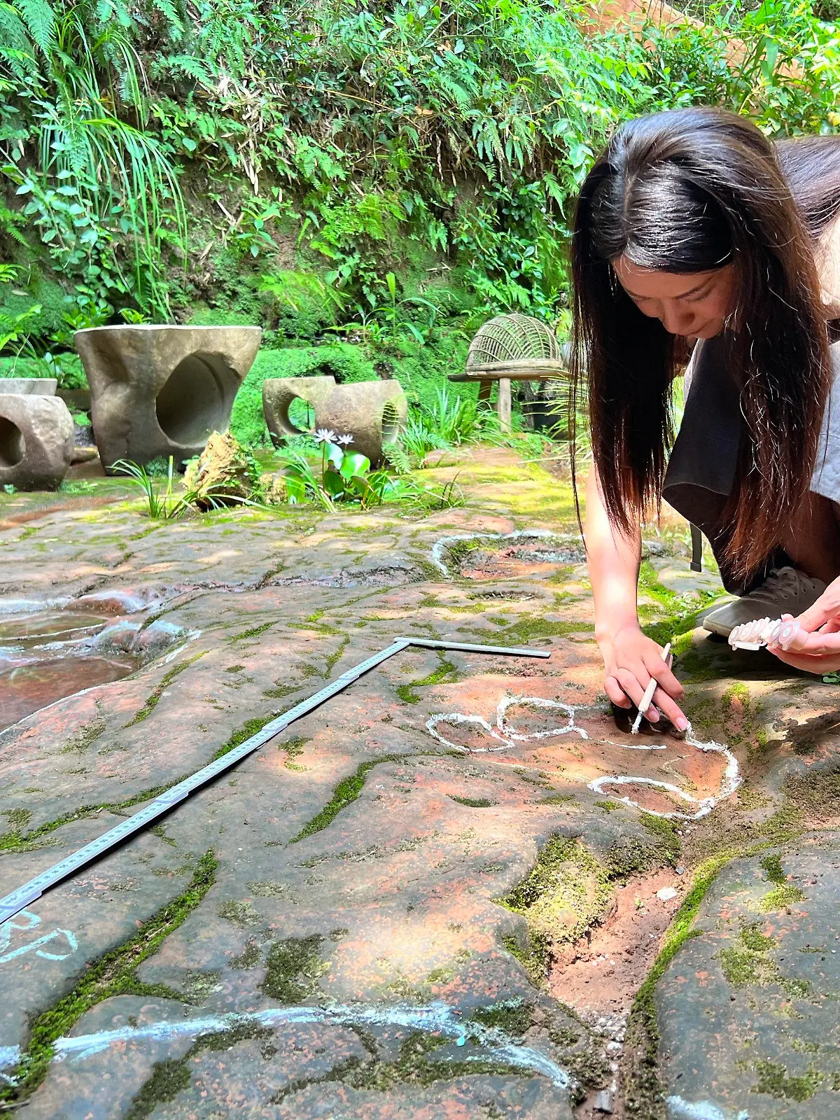 HANDOUT - 21.07.2022, China, Leshan: Eine Wissenschaftlerin im Forscherteam von Lida Xing untersucht die etwa 100 Millionen Jahre alte Dinosaurier-Fußabdrücke. Wie die staatliche Nachrichtenagentur Xinhua berichtete, waren dem Dinosaurier-Enthusiasten Ou Hongtao auffällige Bodenvertiefungen im Garten des Restaurants in der Stadt Leshan ins Auge gefallen. Später bestätigte ein Team professioneller Paläontologen die Entdeckung. Demnach handelte es sich um die Abdrücke zweier etwa acht Meter langer Sauropoden aus der frühen Kreidezeit. (zu dpa: "Gast findet Dinosaurier-Fußabdrücke in chinesischem Restaurant ") Foto: ---/Lida Xing Team/dpa - ACHTUNG: Nur zur redaktionellen Verwendung im Zusammenhang mit der aktuellen Berichterstattung und nur mit vollständiger Nennung des vorstehenden Credits +++ dpa-Bildfunk +++