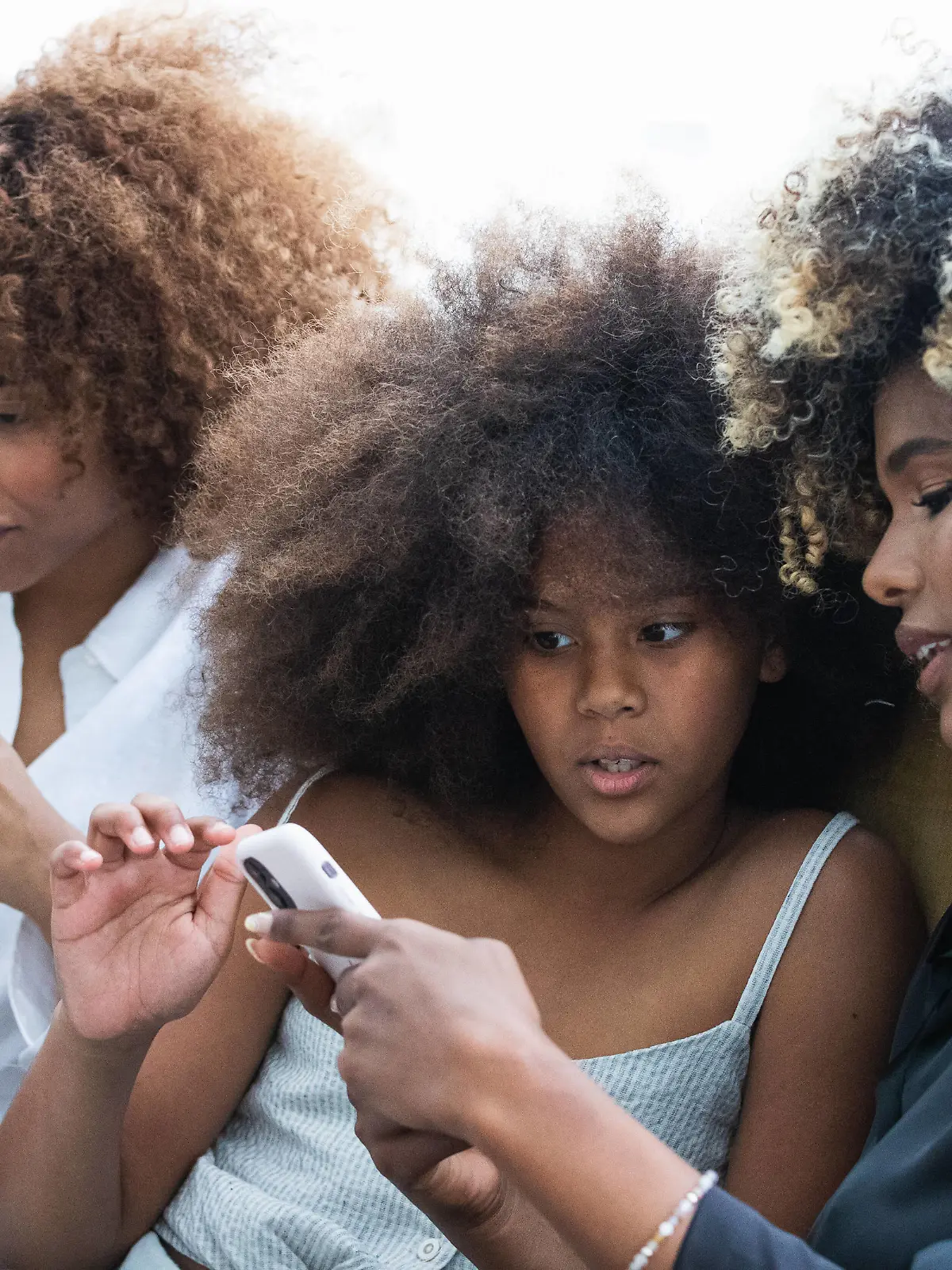Creative Highlights Symbolbilder Happy African American women and girl using smartphone and smiling while chilling on comfortable couch on weekend day at home together, Model released PauNovell_ThreeAfrosStudio_77.jpg Copyright: xPauxNovellx