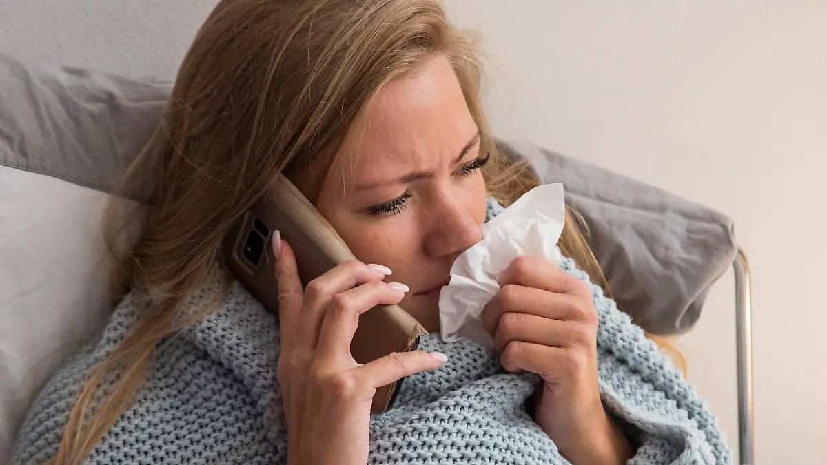 ILLUSTRATION - Eine Frau liegt am 09.10.2019 in Hamburg in einer Wohnung krank im Bett und telefoniert waehrend sie sich die Nase putzt (gestellte Szene). Foto: Christin Klose || Modellfreigabe vorhanden