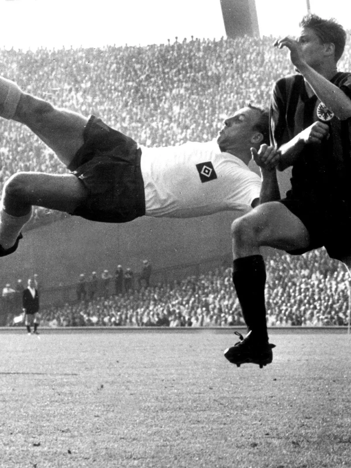 ARCHIV - HSV-Mittelstürmer Uwe Seeler (l) versucht mit einem Fallrückzieher beim Gruppenspiel um den DFB-Pokal zum Erfolg zu kommen. Eintracht-Abwehrspieler Friedel Lutz bedrängt ihn im Hamburger Volksparkstadion. (Archivfoto vom 03.06.1961). Uwe Seeler, der Ehrenspielführer der deutschen Fußball- Nationalmannschaft und ehemalige Spieler des Hamburger SV, feiert am 5. November seinen 70. Geburtstag. Foto:  Lothar Heidtmann (zu dpa-KORR: "Seeler genießt «Unruhestand» - Kritik an van Buyten und Boulahrouz" vom 01.11.2006) +++(c) dpa - Bildfunk+++