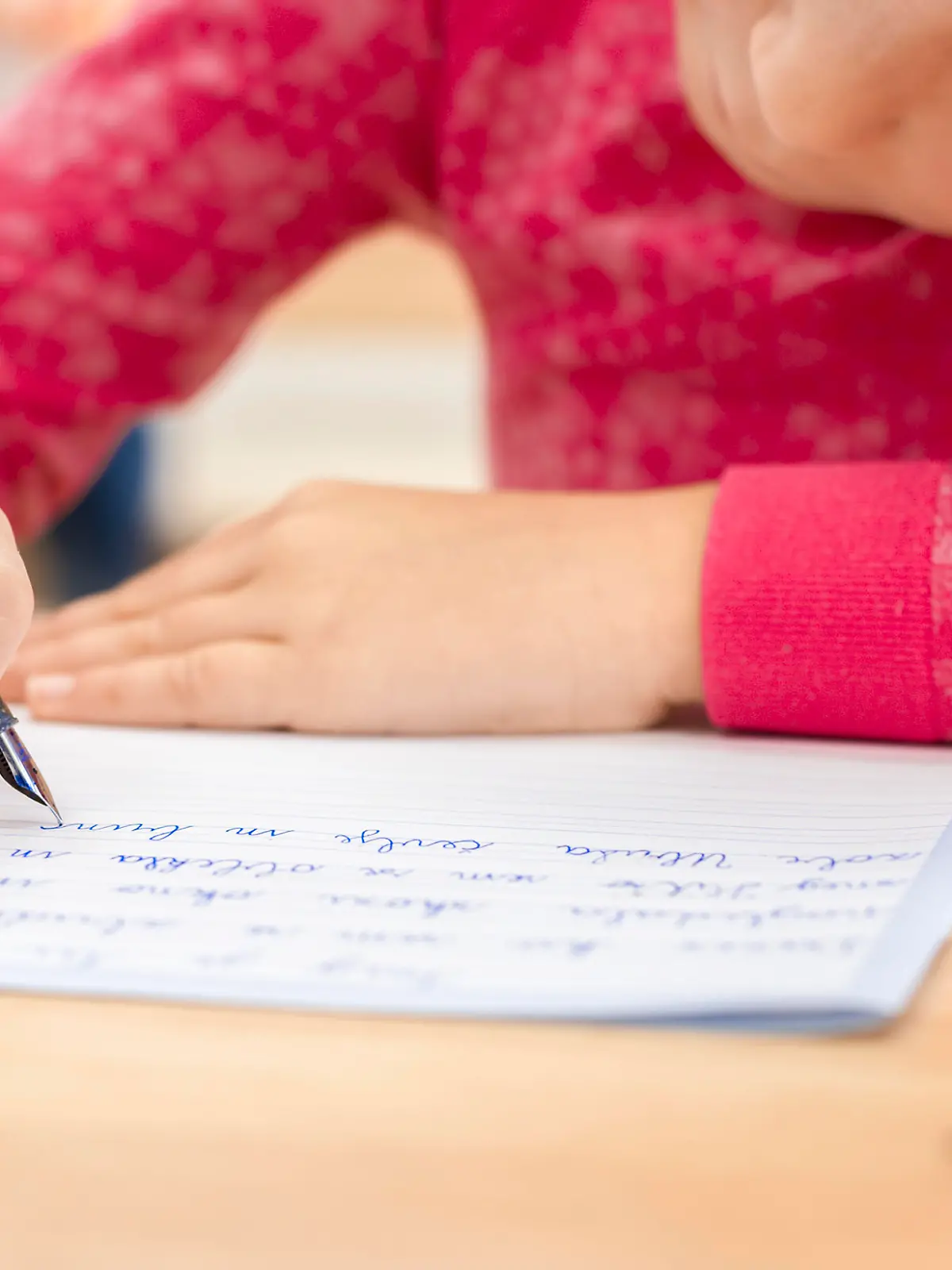 Schoolgirl writing in notebook in classroom.