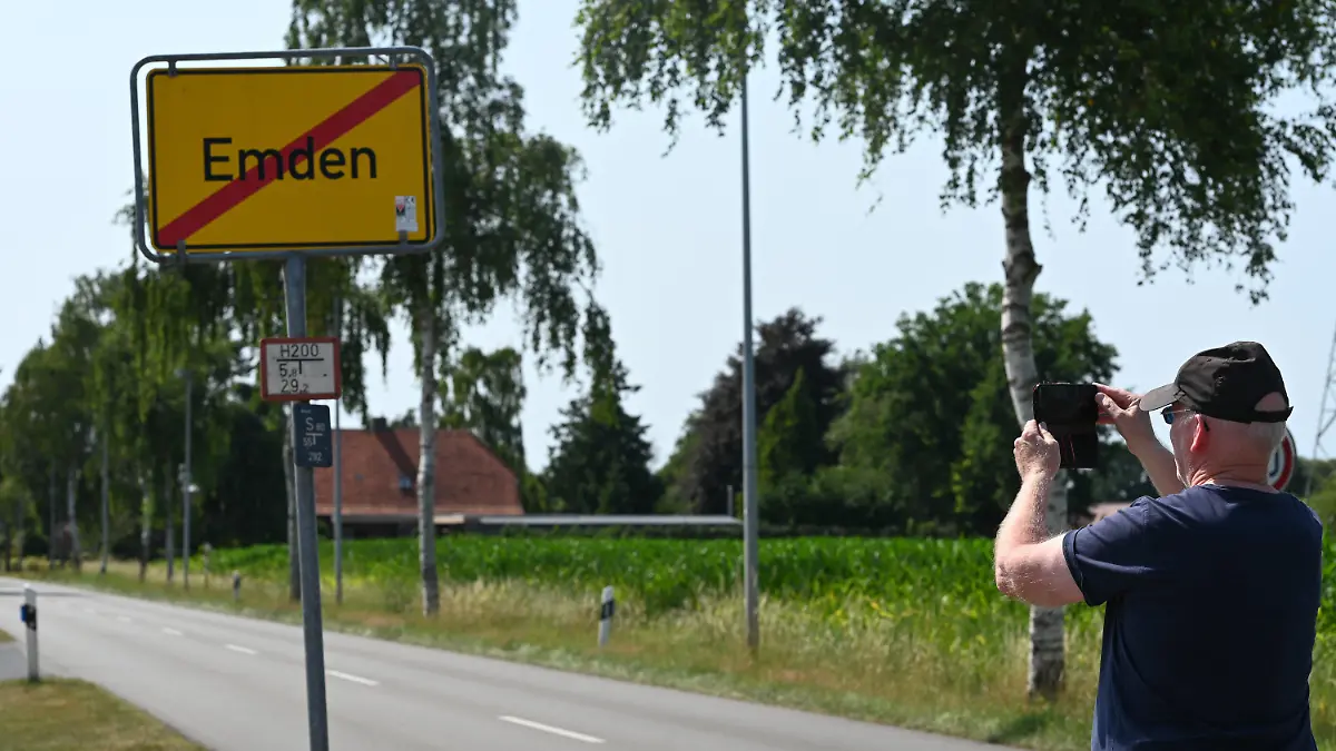 19.07.2022, Niedersachsen, Veenhusen: Ein Mann macht Fotos vom Ortsausgangsschild «Emden» in der ostfriesischen Gemeinde Moormerland im Ortsteil Veenhusen. Unbekannte haben in der ostfriesischen Gemeinde Moormerland im Ortsteil Veenhusen gleich drei gelbe Ortsschilder abmontiert und mit Ortschildern aus Emden ersetzt. Bislang seien die Veenhusen-Schilder, die pro Stück rund 350 Euro kosten, noch nicht wieder aufgetaucht. Foto: Lars Klemmer/dpa +++ dpa-Bildfunk +++