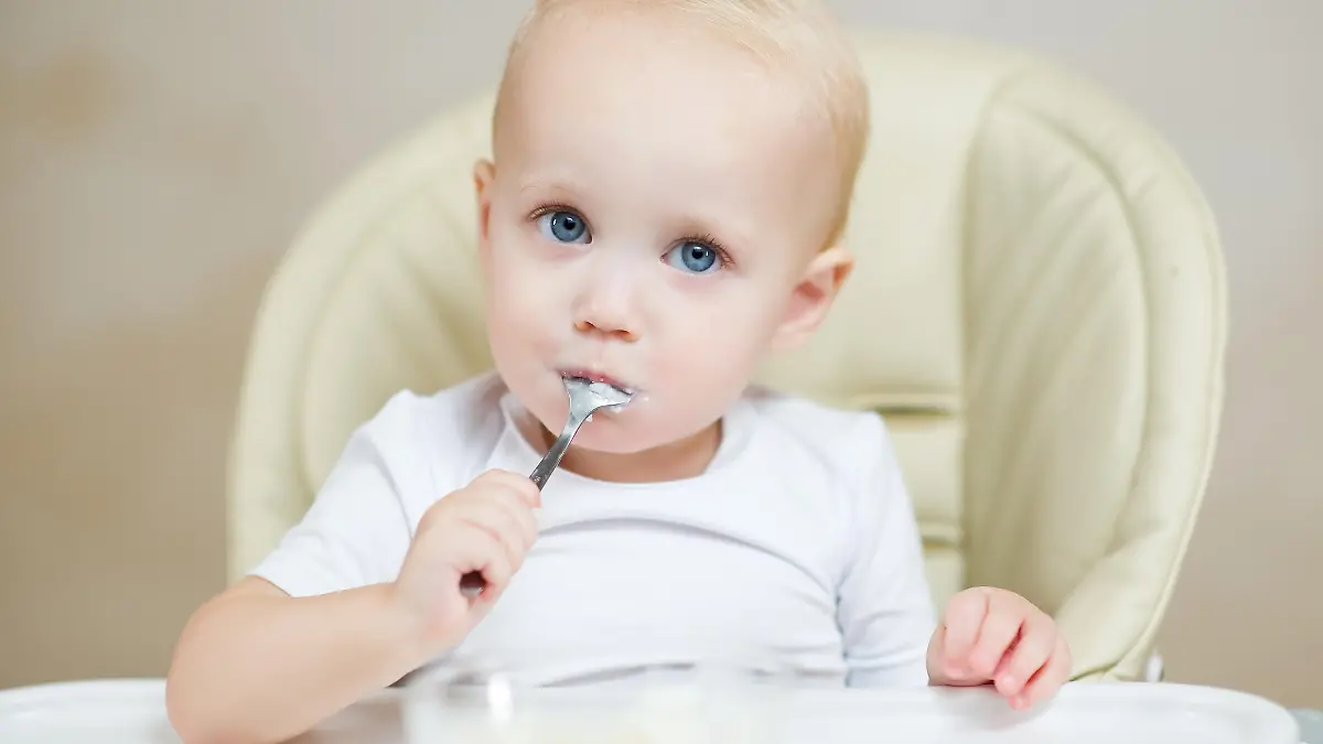 Baby isst Brei mit eigenem Löffel