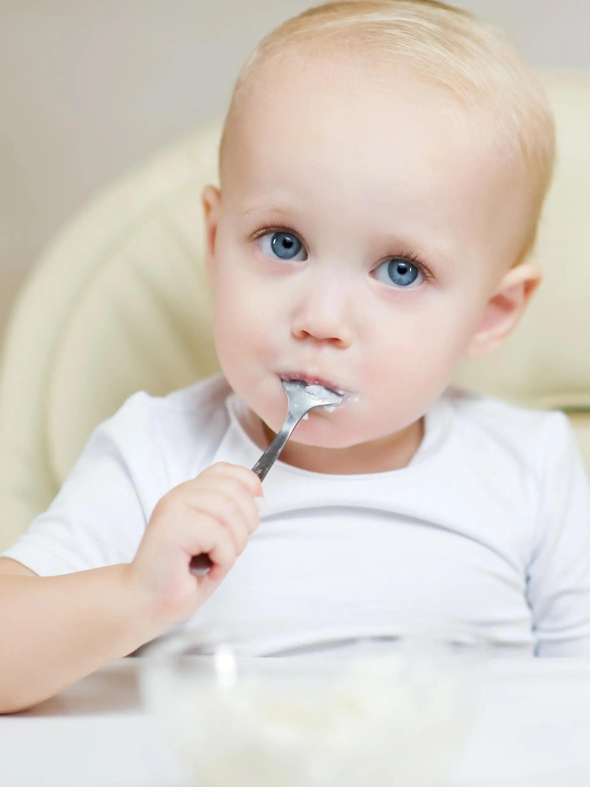 Baby isst Brei mit eigenem Löffel