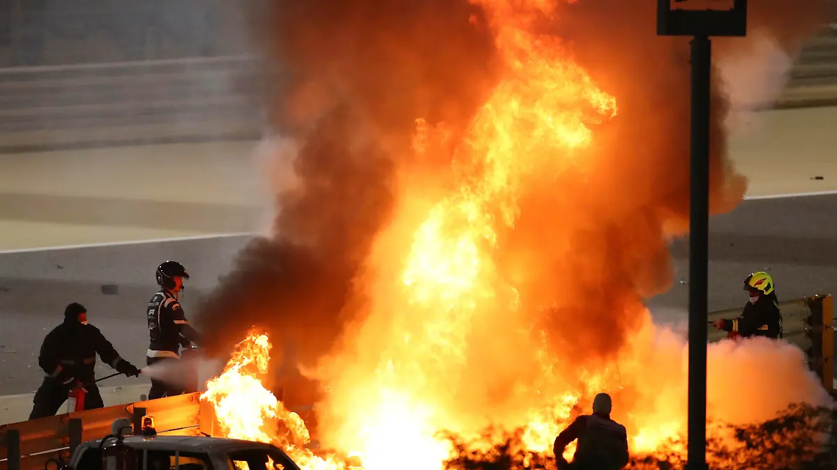 FILE - Staff extinguish flames from Haas driver Romain Grosjean's car after a crash during the Formula One race in Bahrain International Circuit in Sakhir, Bahrain, in this Sunday, Nov. 29, 2020, file photo. Mercedes announced Wednesday, May 5, 2021, that Grosjean will drive Lewis Hamilton’s 2019 championship-winning car at the French Grand Prix on June 27 before a full test day at Circuit Paul Ricard two days later. (Brynn Lennon/Pool via AP, File)